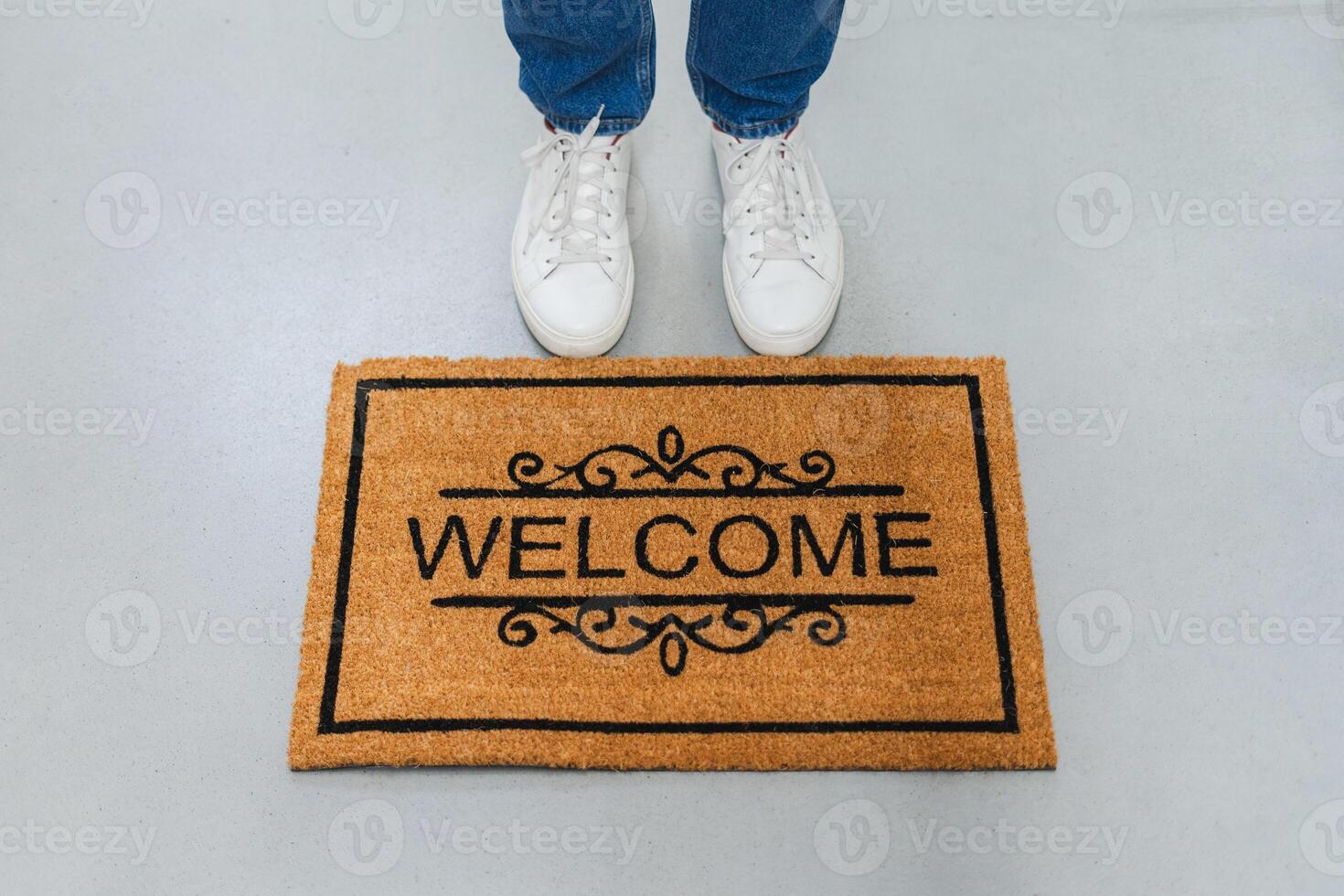 Door mat with word Welcome and stylish boots on floor. Top view. Cropped photo