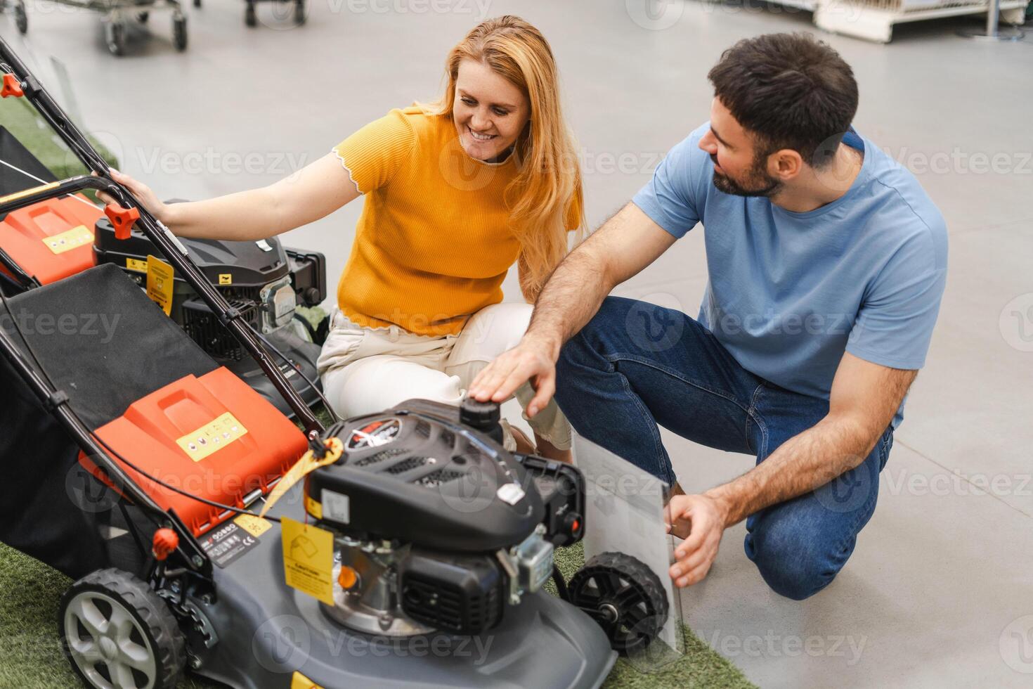 Happy young family choosing lawn mower while coming to the garden tools store photo