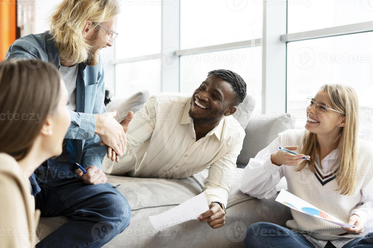 Diverse team of professionals collaborating and shaking hands in a modern office photo