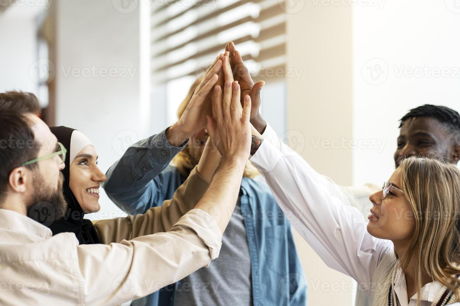 Diverse, multiracial group of people giving high five in modern office, Teamwork concept photo