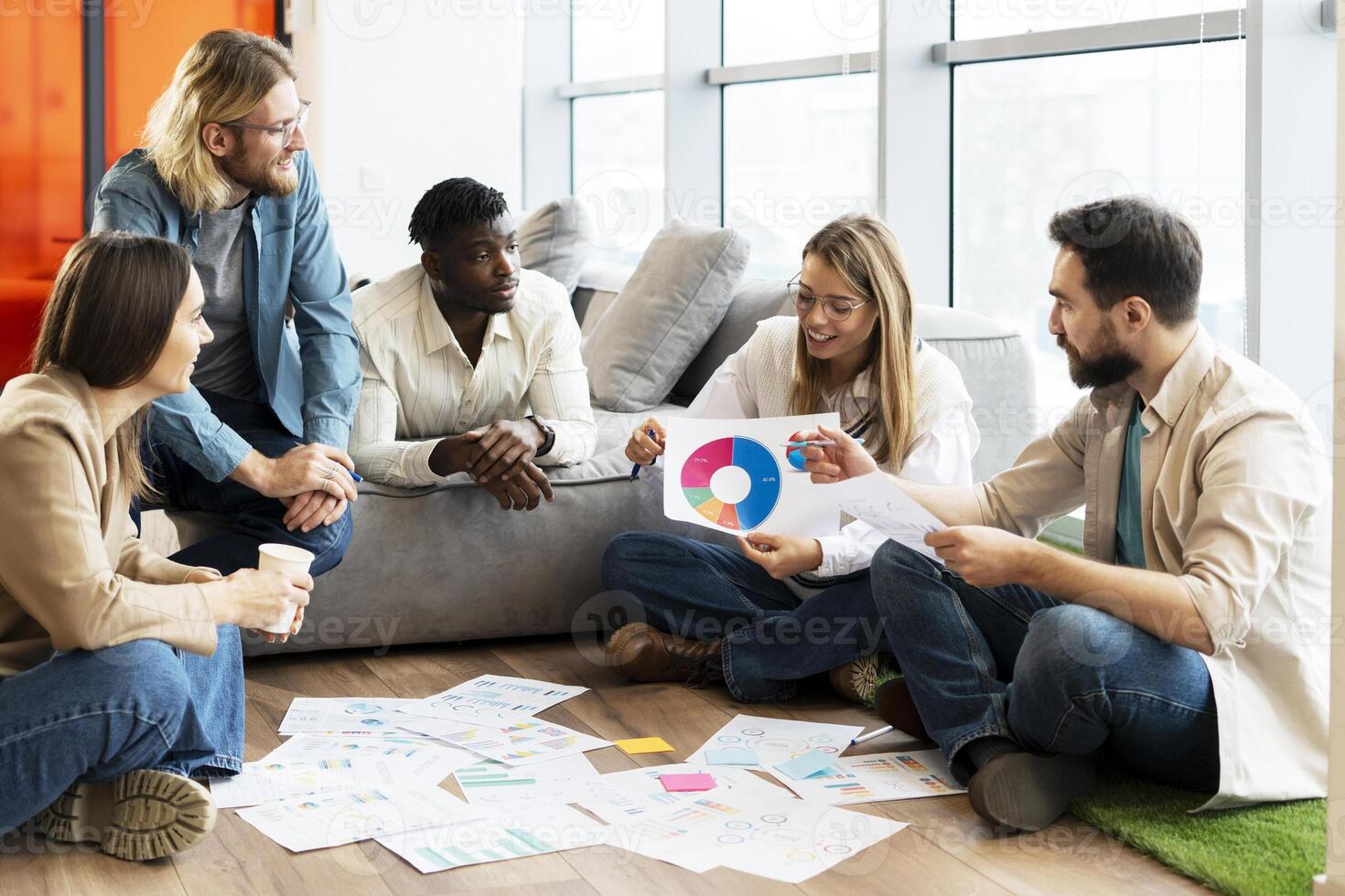 Team of young professionals is brainstorming new project using data visualization on floor in office photo