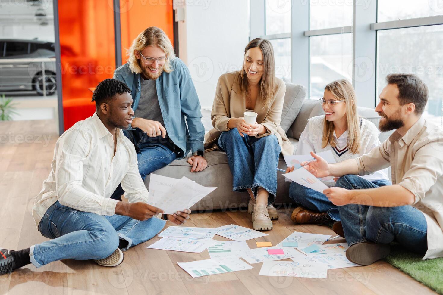 Marketing team having brainstorming session discussing documents on the floor photo
