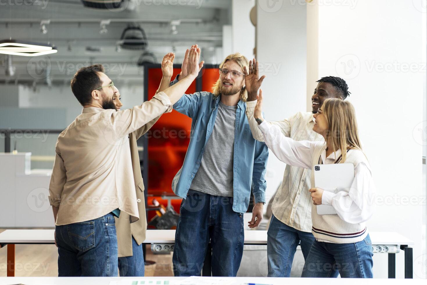 Diverse business team giving high five, celebrating success in modern office photo