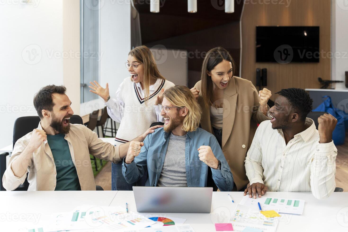 Excited diverse team, happy colleagues celebrating success in modern office photo