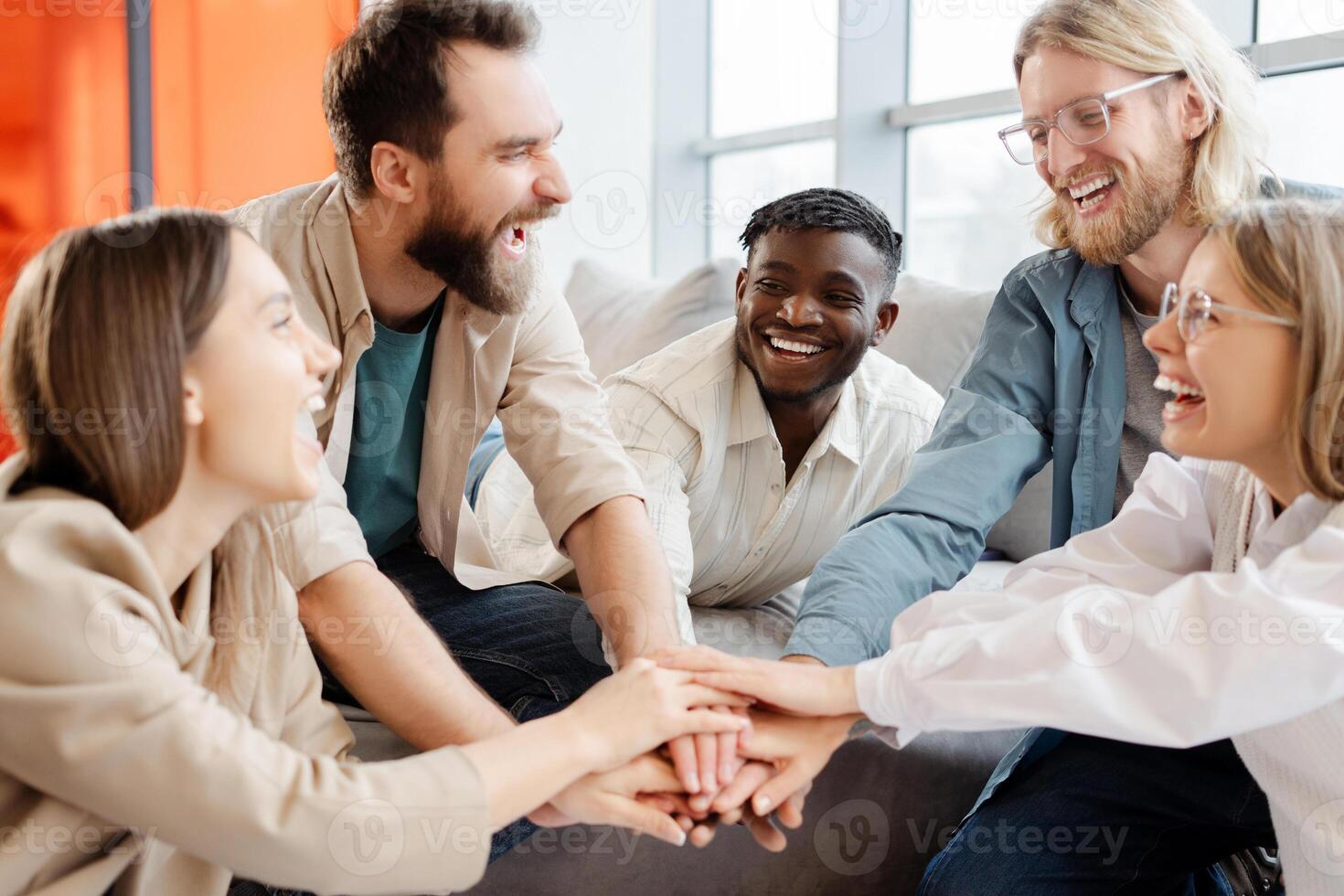 Group of diverse people joining hands together smiling and laughing photo