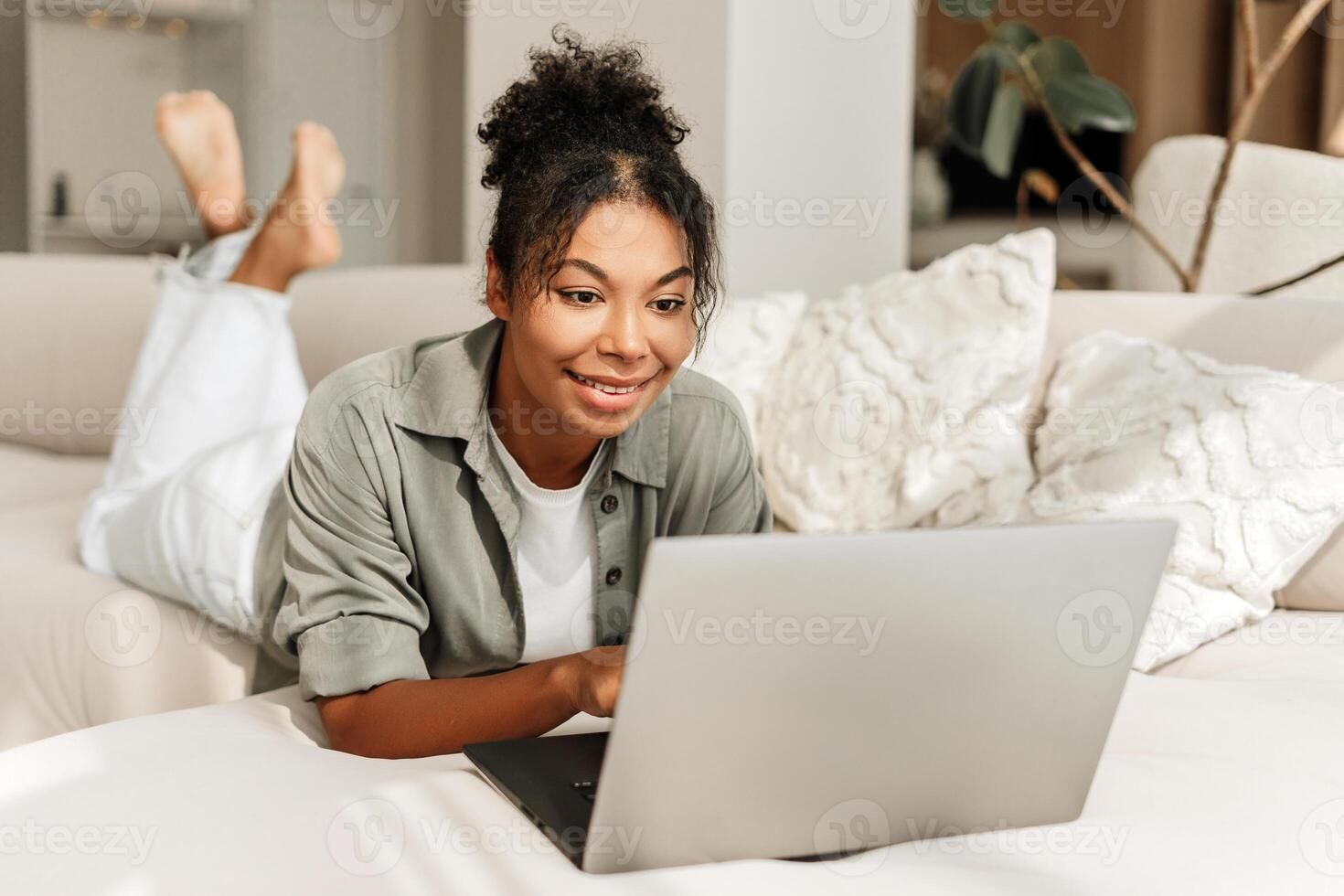 Young woman relaxing on couch using laptop at home photo