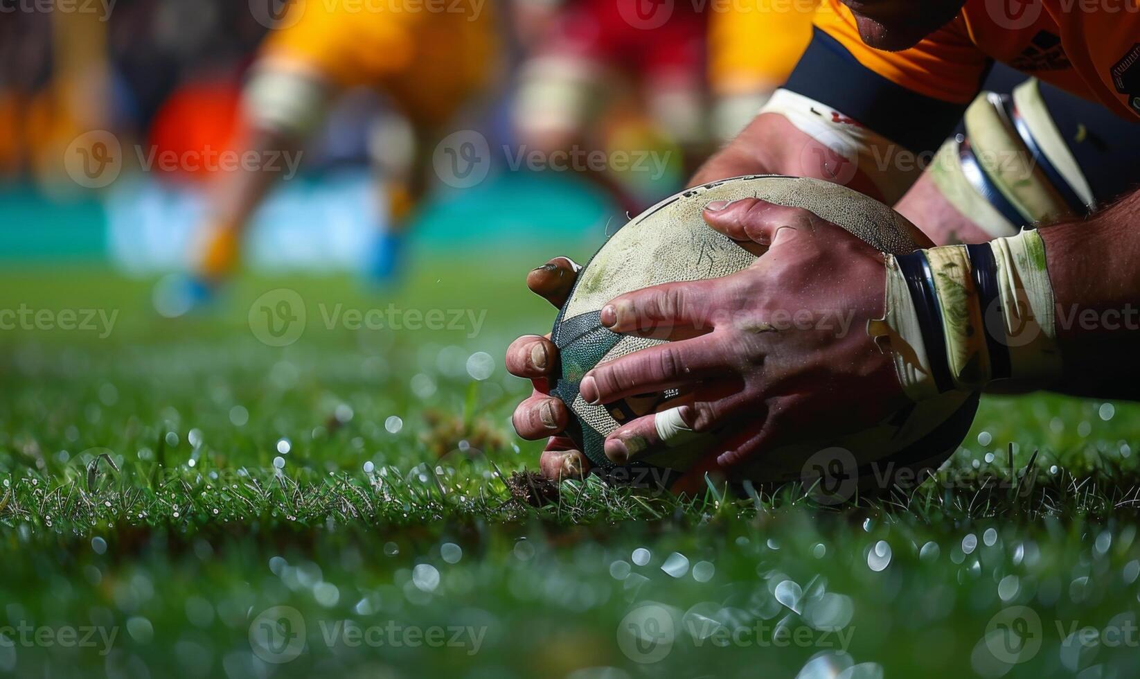 A rugby player's hands gripping the ball, with the field and players in the background photo
