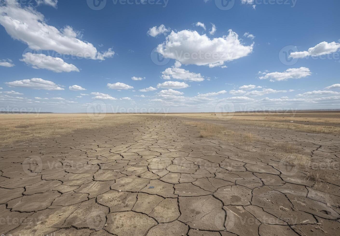 A dry, cracked field with blue sky and clouds photo