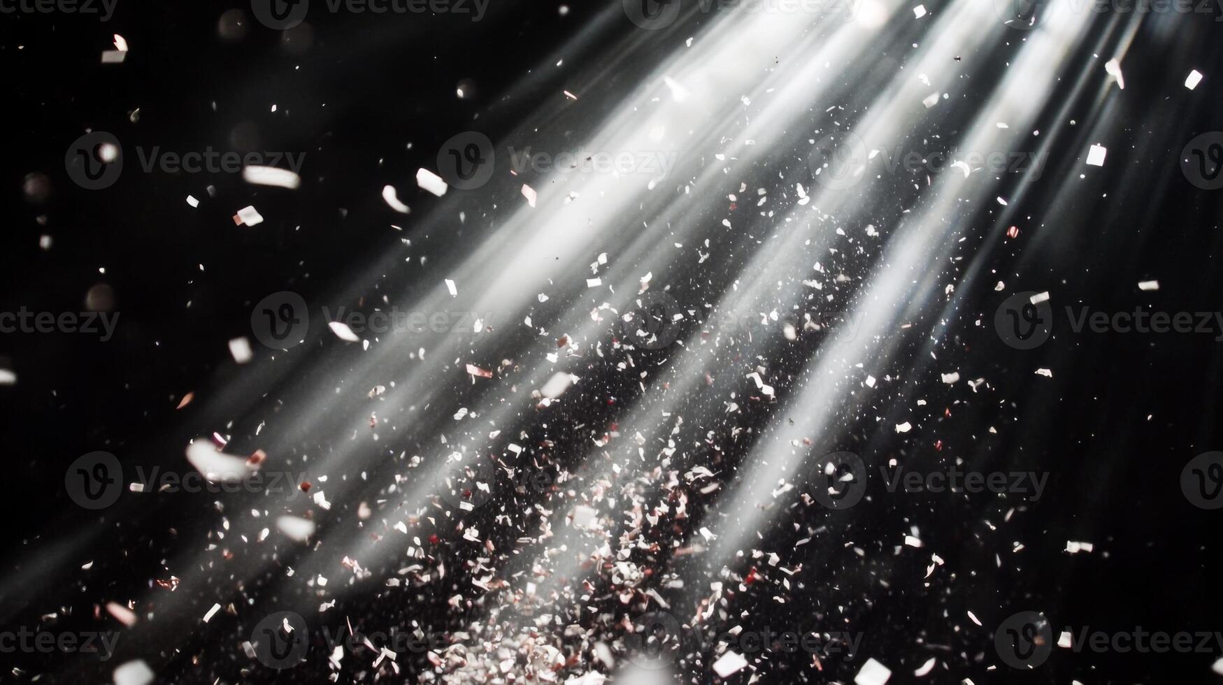 Dynamic image of swirling confetti, caught in beams of white light, with the dark background enhancing the brightness and movement of the scene photo