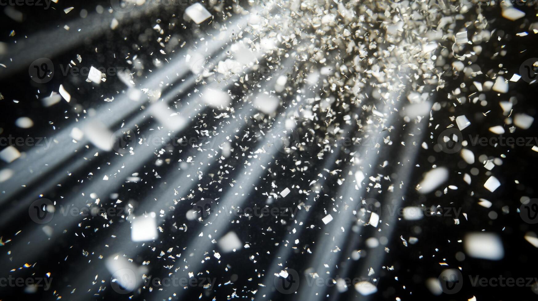 Dynamic image of swirling confetti, caught in beams of white light, with the dark background enhancing the brightness and movement of the scene photo