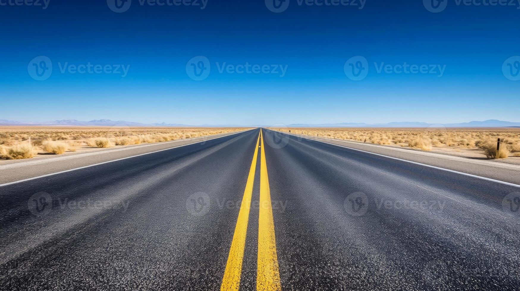 A wide-angle shot of an empty highway stretching into the horizon under a clear blue sky photo