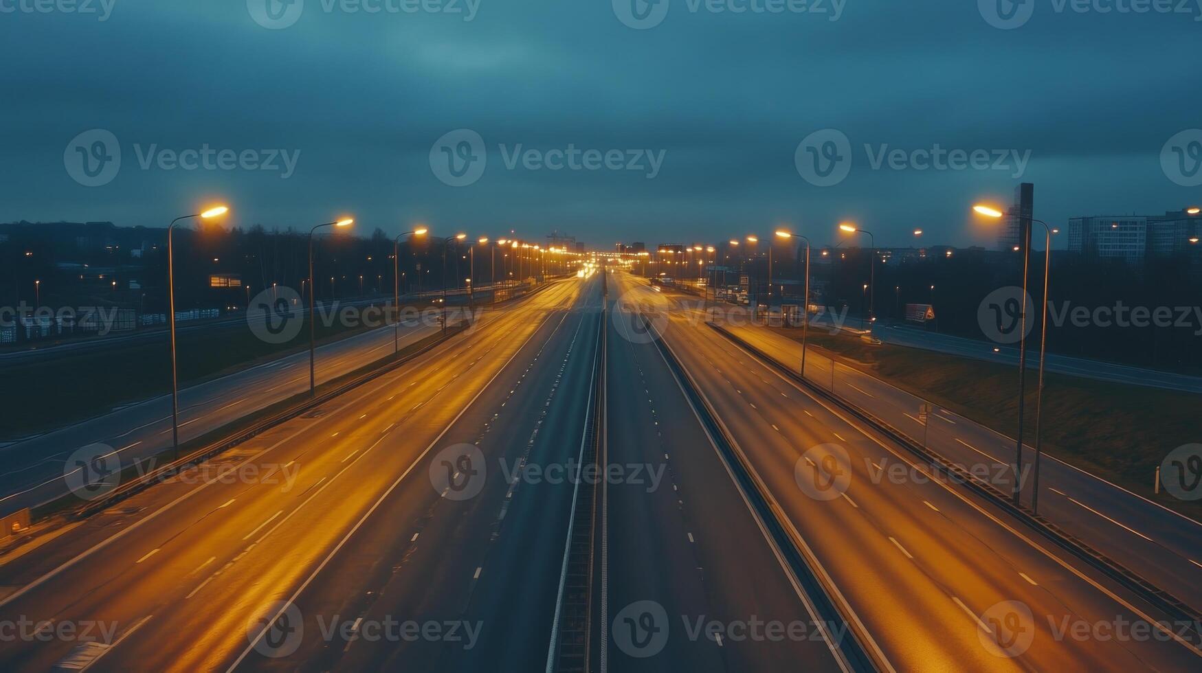 A quiet highway at dusk, illuminated by streetlights, with a soft glow on the asphalt photo