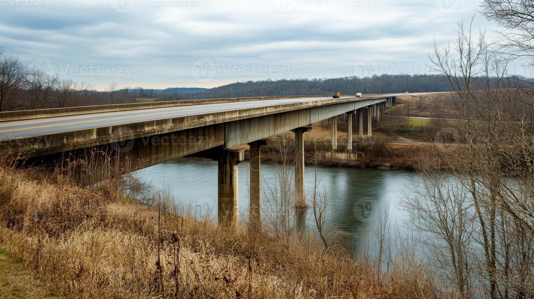 An expansive highway bridge crossing over a river, surrounded by nature and no signs of human activity photo