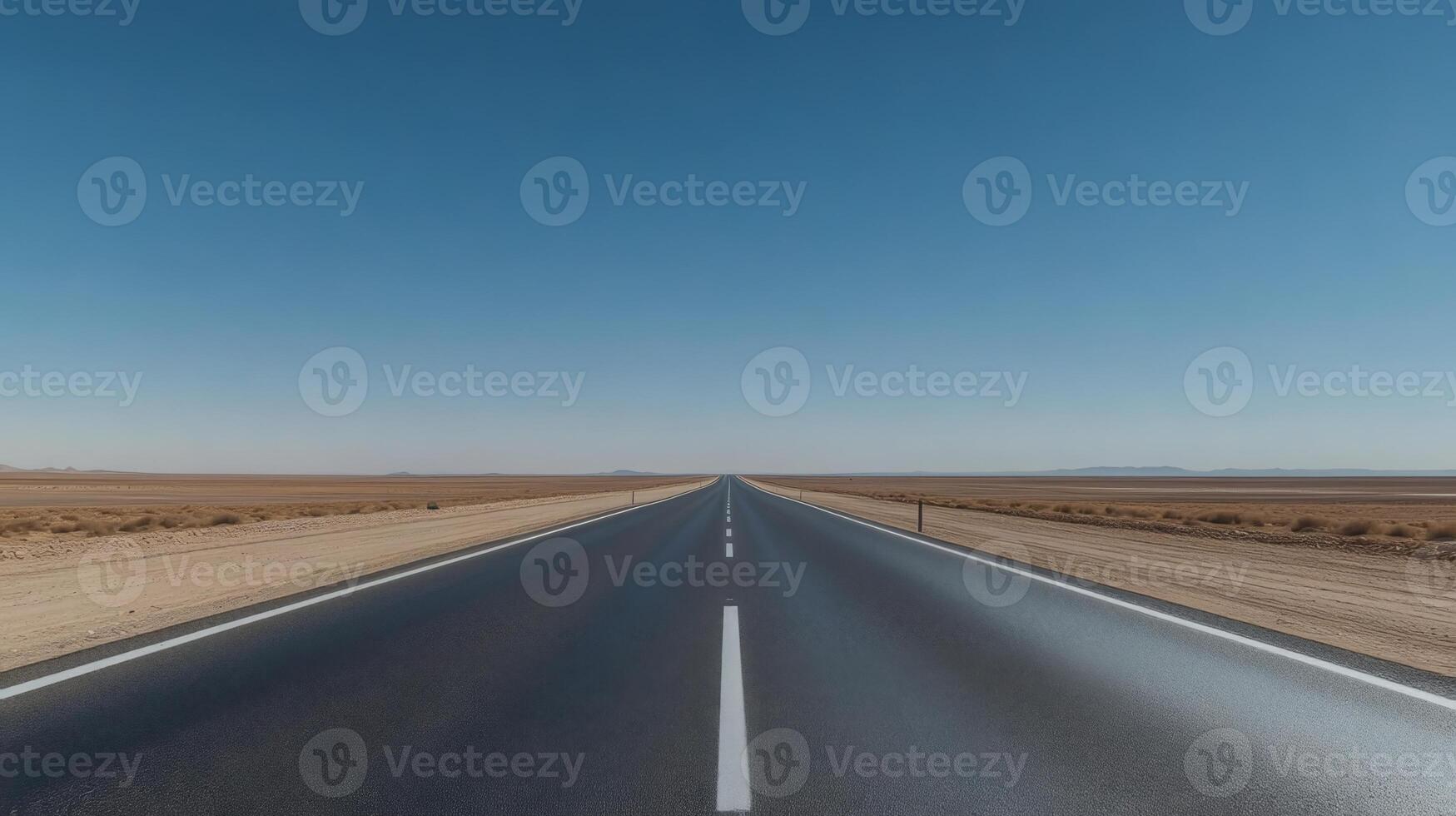A wide-angle shot of an empty highway stretching into the horizon under a clear blue sky photo
