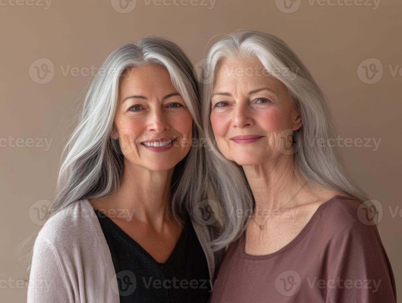 Two women, one in her thirties and one in her sixties, standing close together with soft smiles, against a neutral-toned background photo