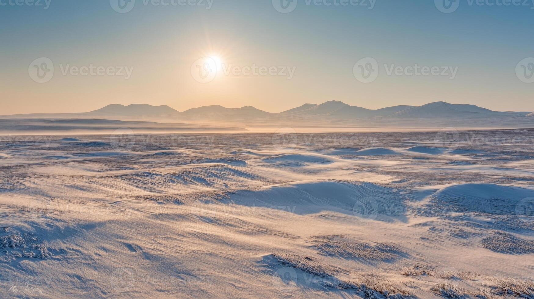 A vast, open tundra under a pale winter sun, with snowdrifts and distant mountain ranges in the background photo