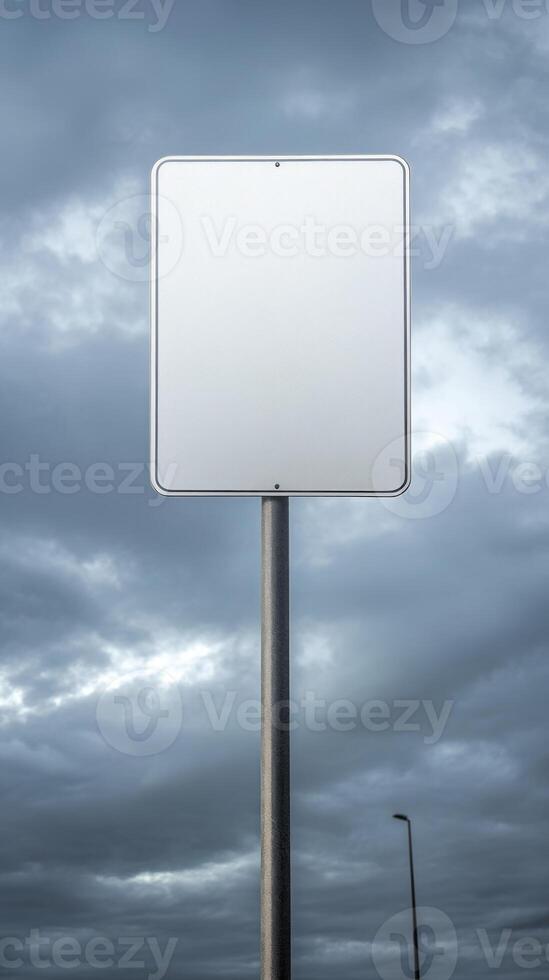Vertical shot of a blank road sign on a tall post, isolated against a cloudy sky, mockup for text photo