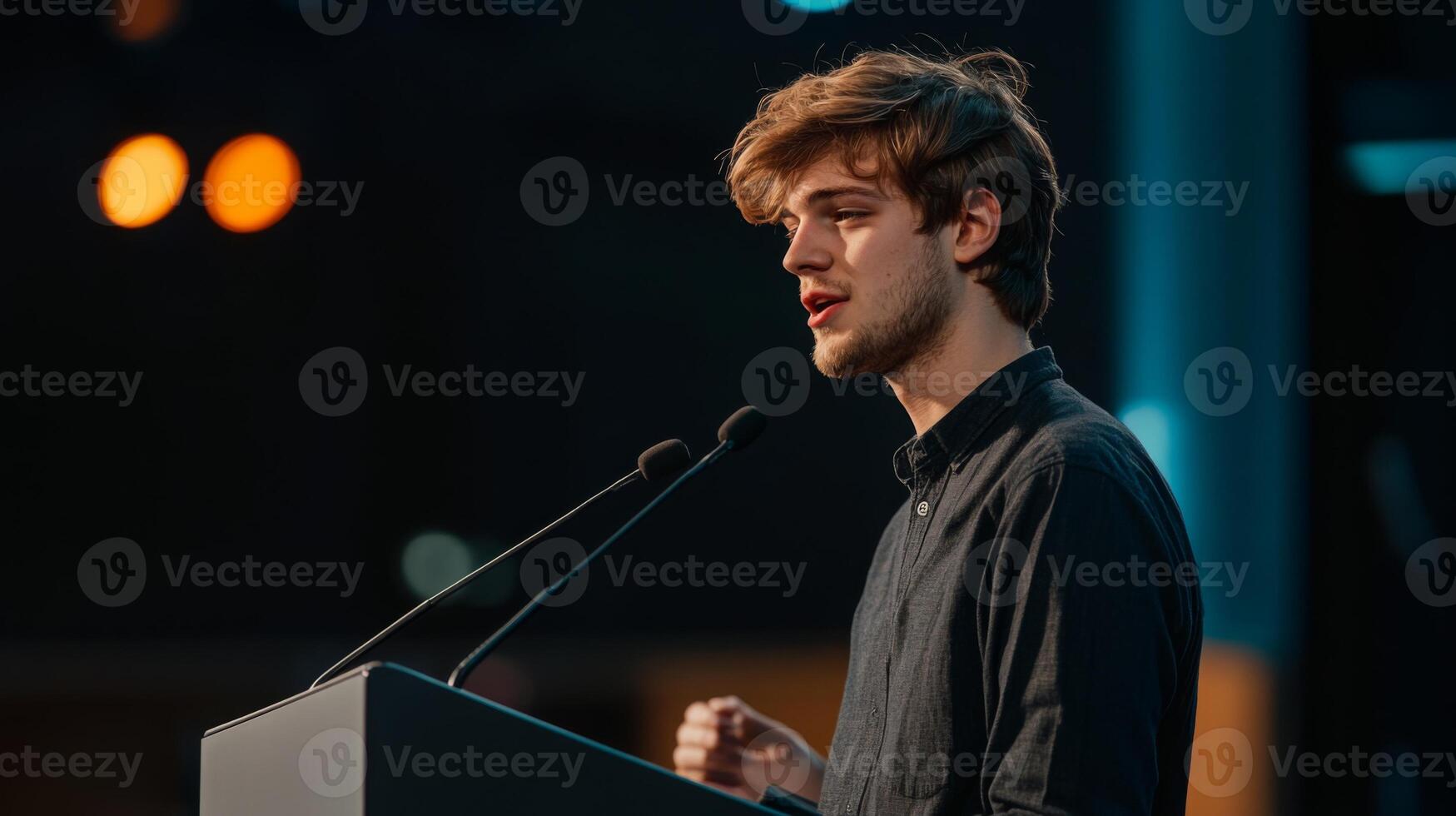 A young man standing at a podium, passionately addressing a conference crowd photo