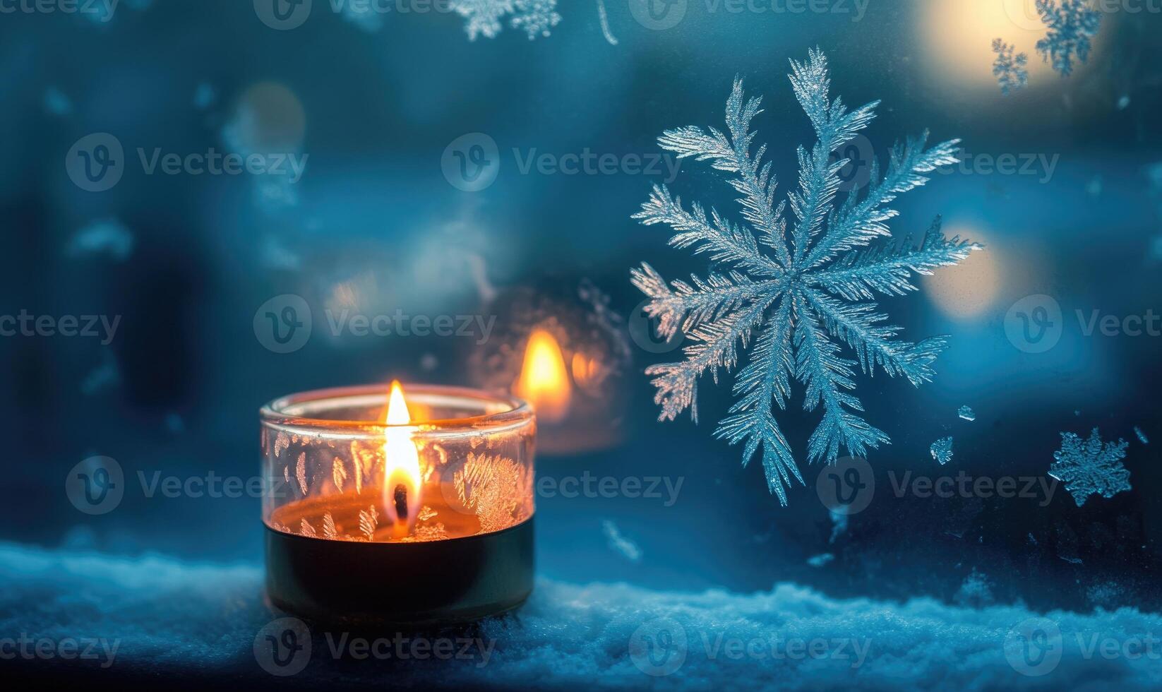 A candle is lit in a glass container on a snowy surface photo