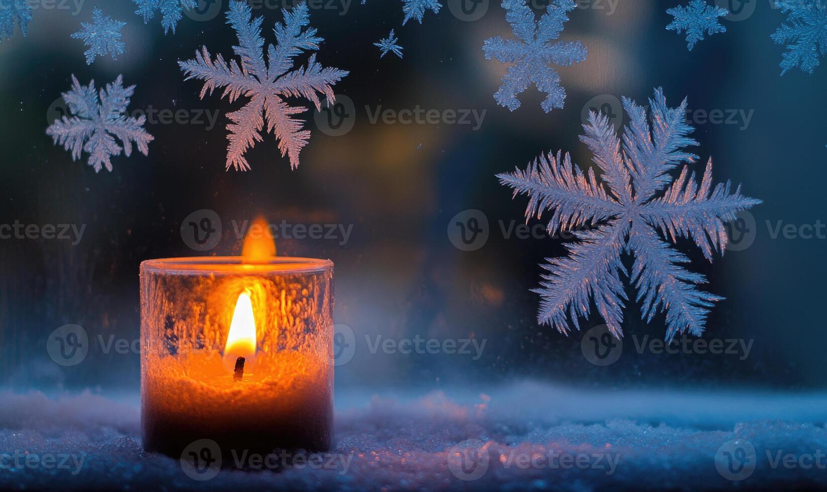 A candle is lit in front of a window with snowflakes falling outside photo