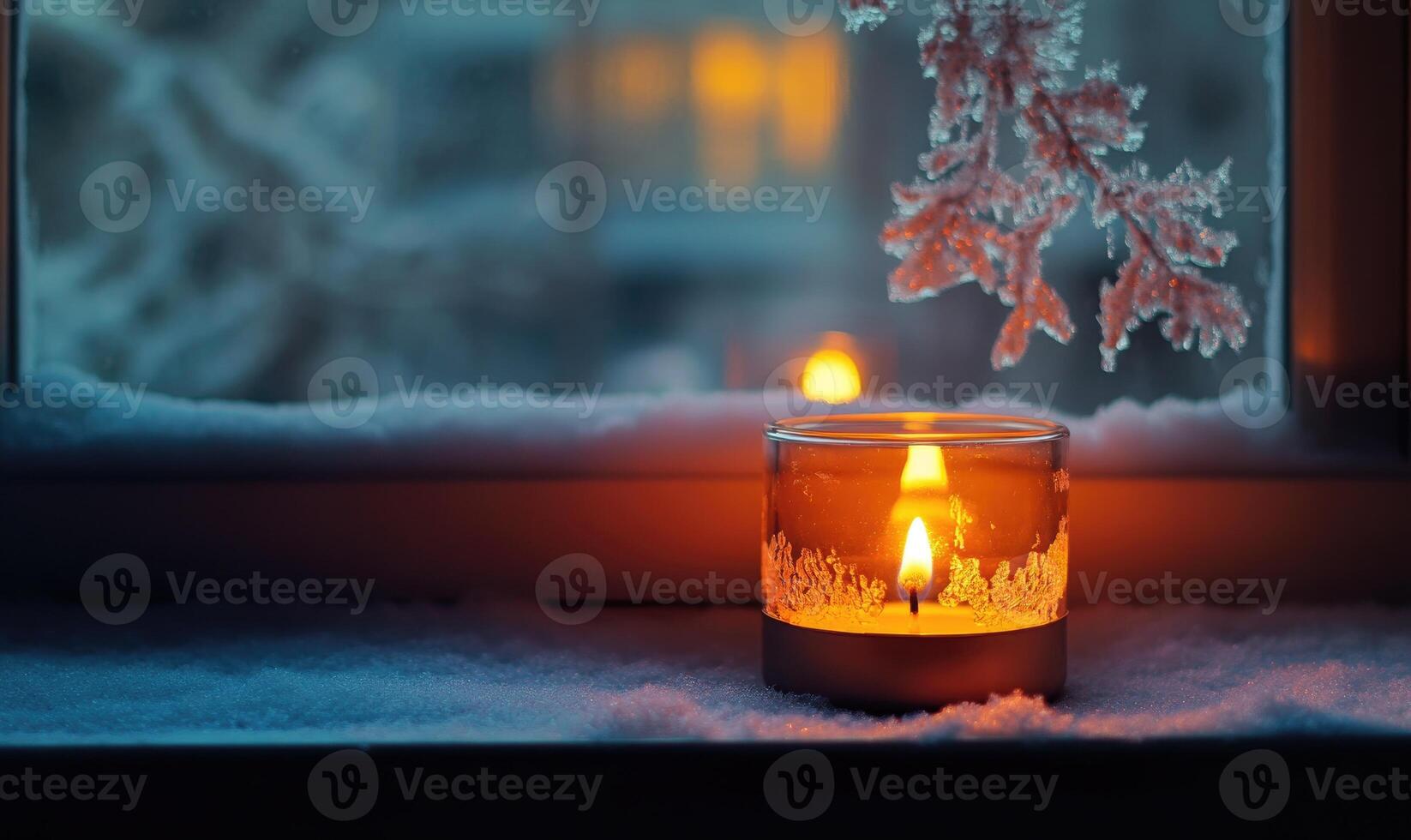 A candle is lit in a glass on a window sill photo