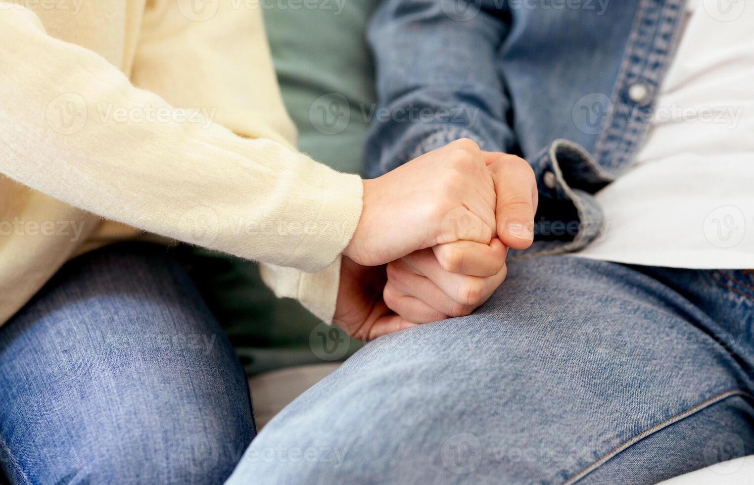 Close view of a pair of individuals clasping hands tightly. photo