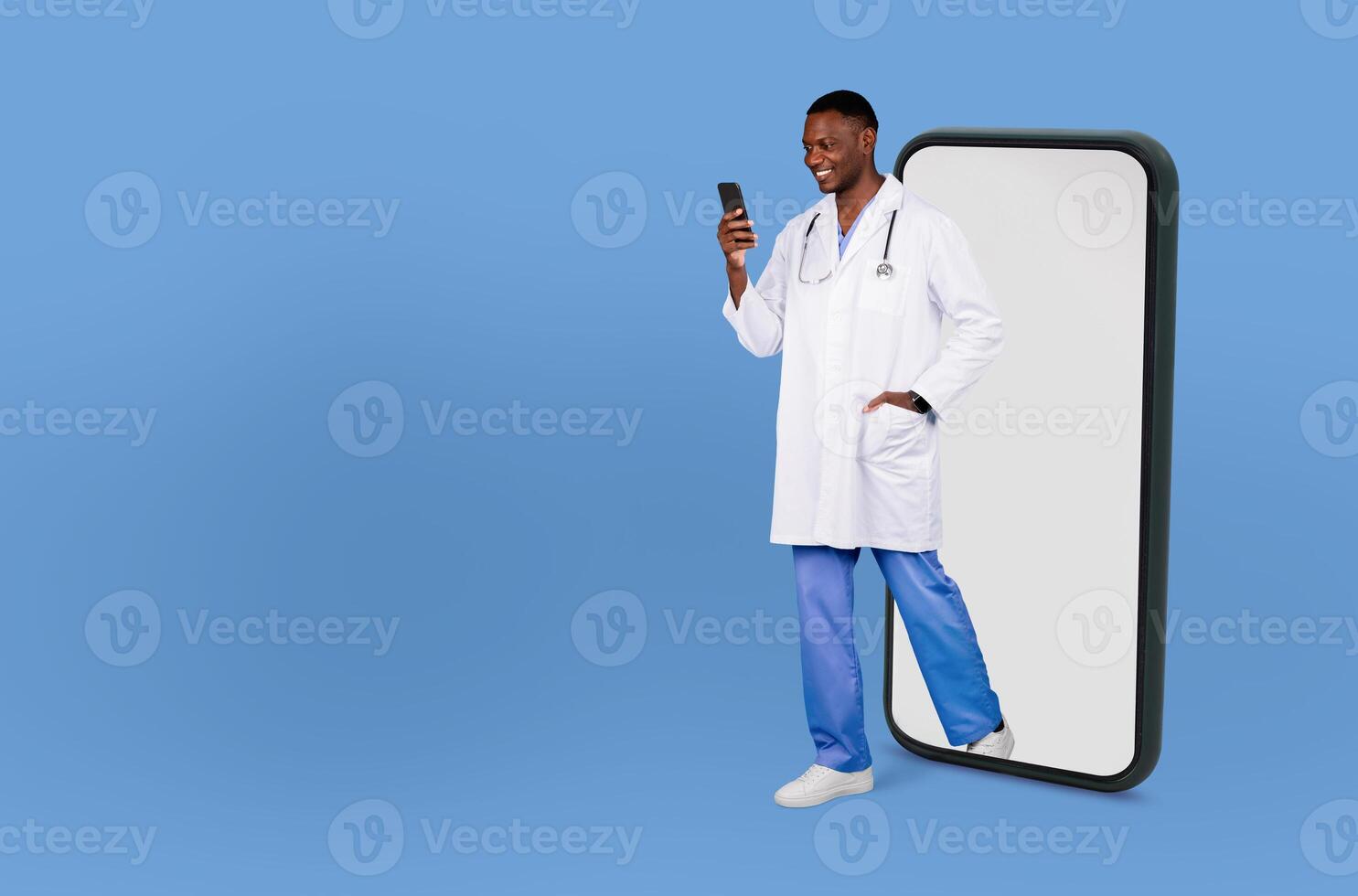 A smiling healthcare professional black man, dressed in a white lab coat and blue scrubs, walks through a giant smartphone screen while looking at his cell phone. photo