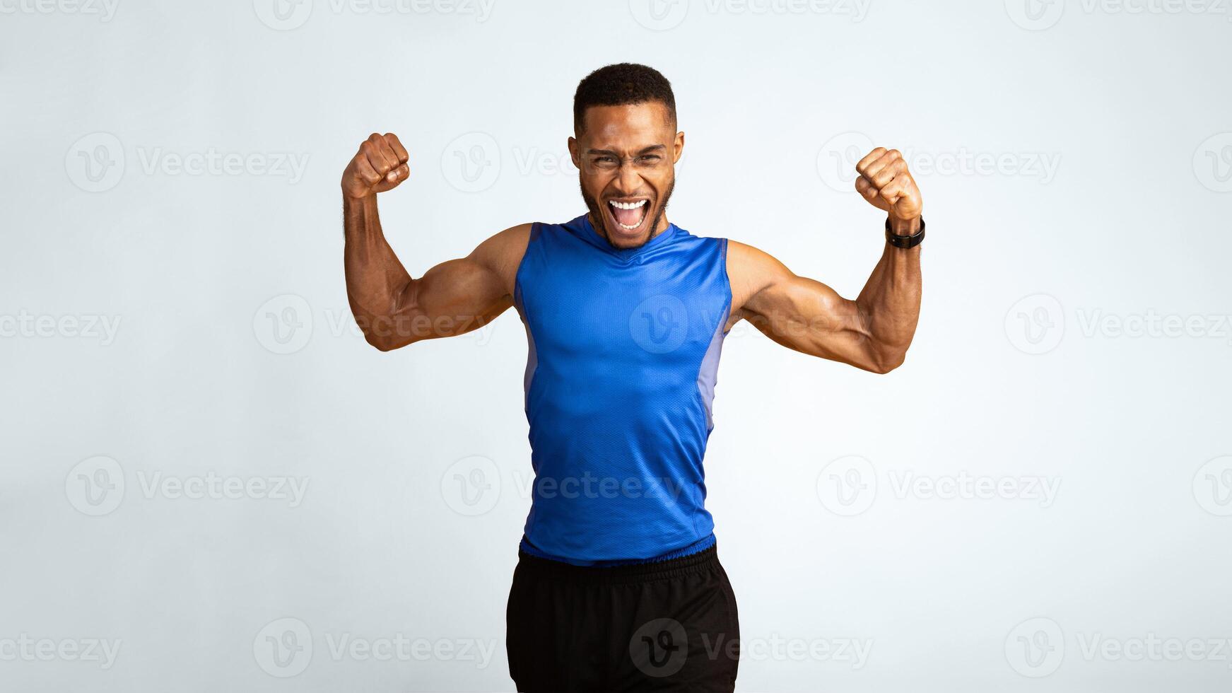 Yes You Can. Emotional black sportsman screaming, raising clenched fists in the air, yellow studio wall, panorama photo