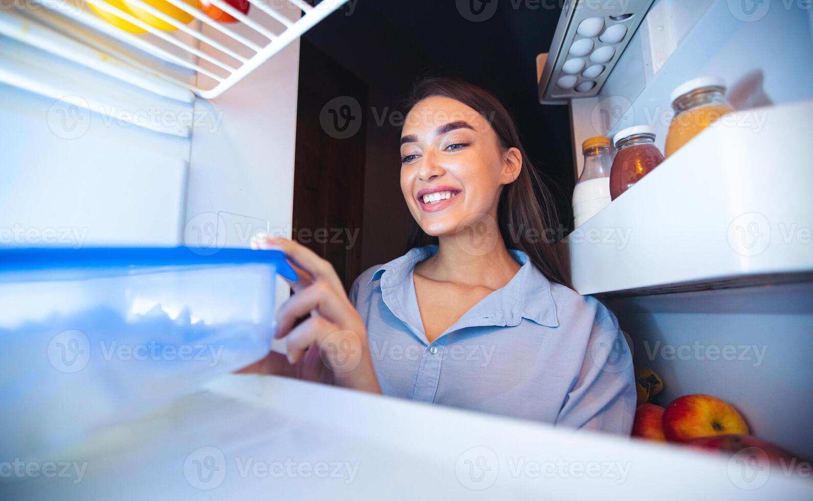 Diet schedule. Cheerful girl taking food container with lunch from fridge, view from inside photo