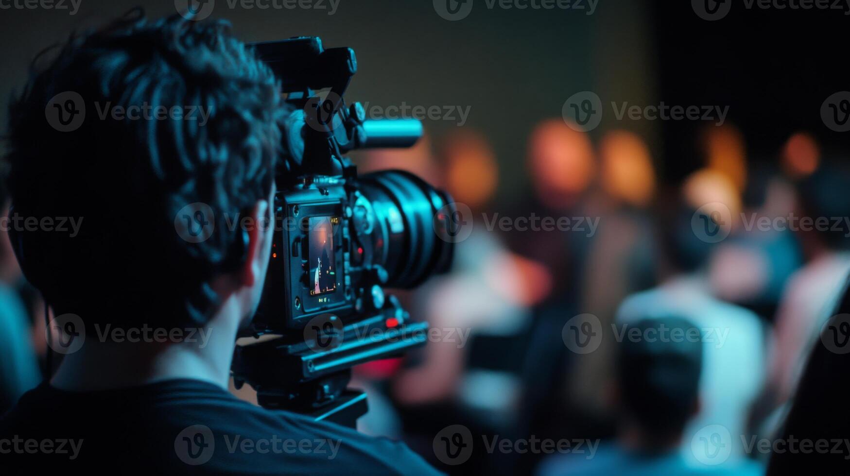 A filmmaker focuses on a live performance, capturing the energy and atmosphere of the dimly lit venue filled with an engaged audience. photo
