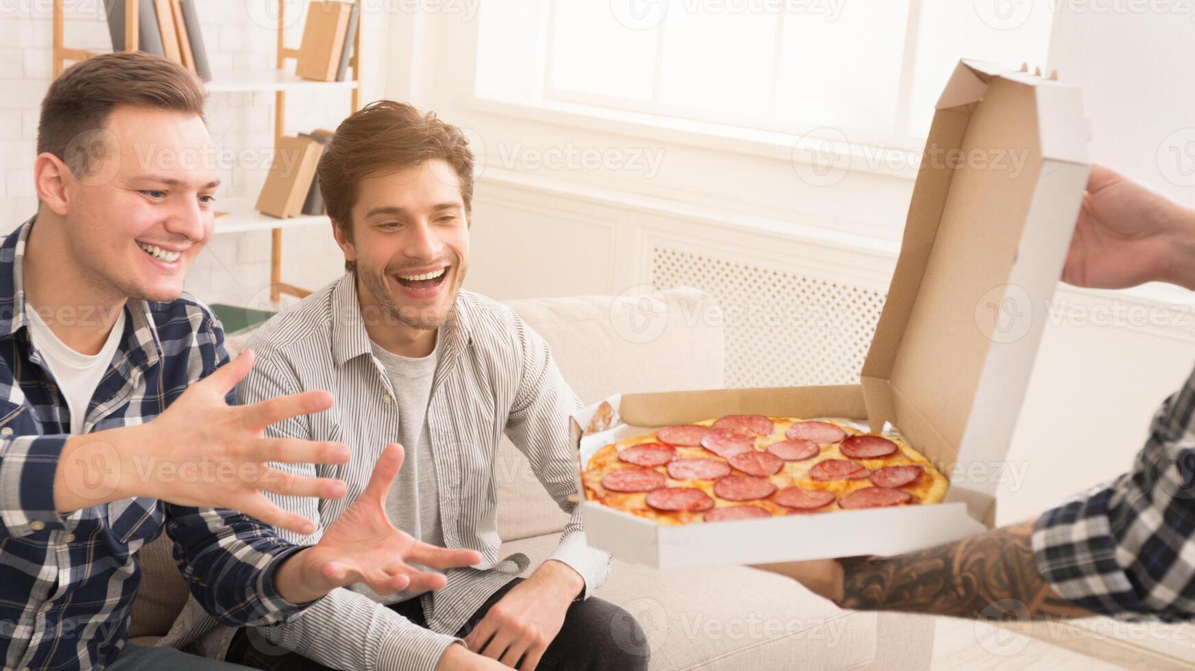 Friends taking slices of hot pizza from delivery box, having home party photo