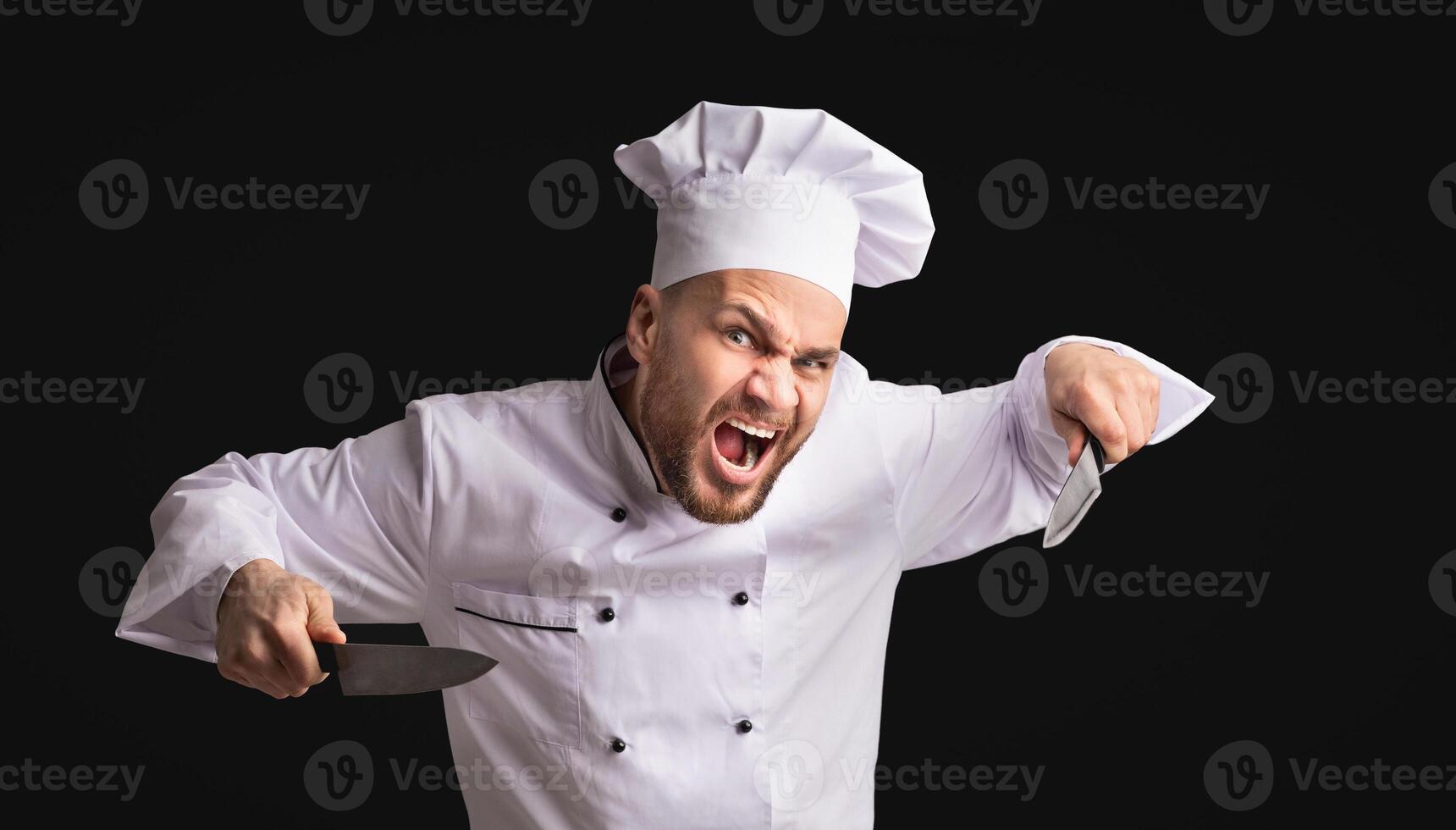 Crazy Aggressive Chef Man Holding Knives Threatening And Looking At Camera Posing Over Black Background In Studio. Panorama photo