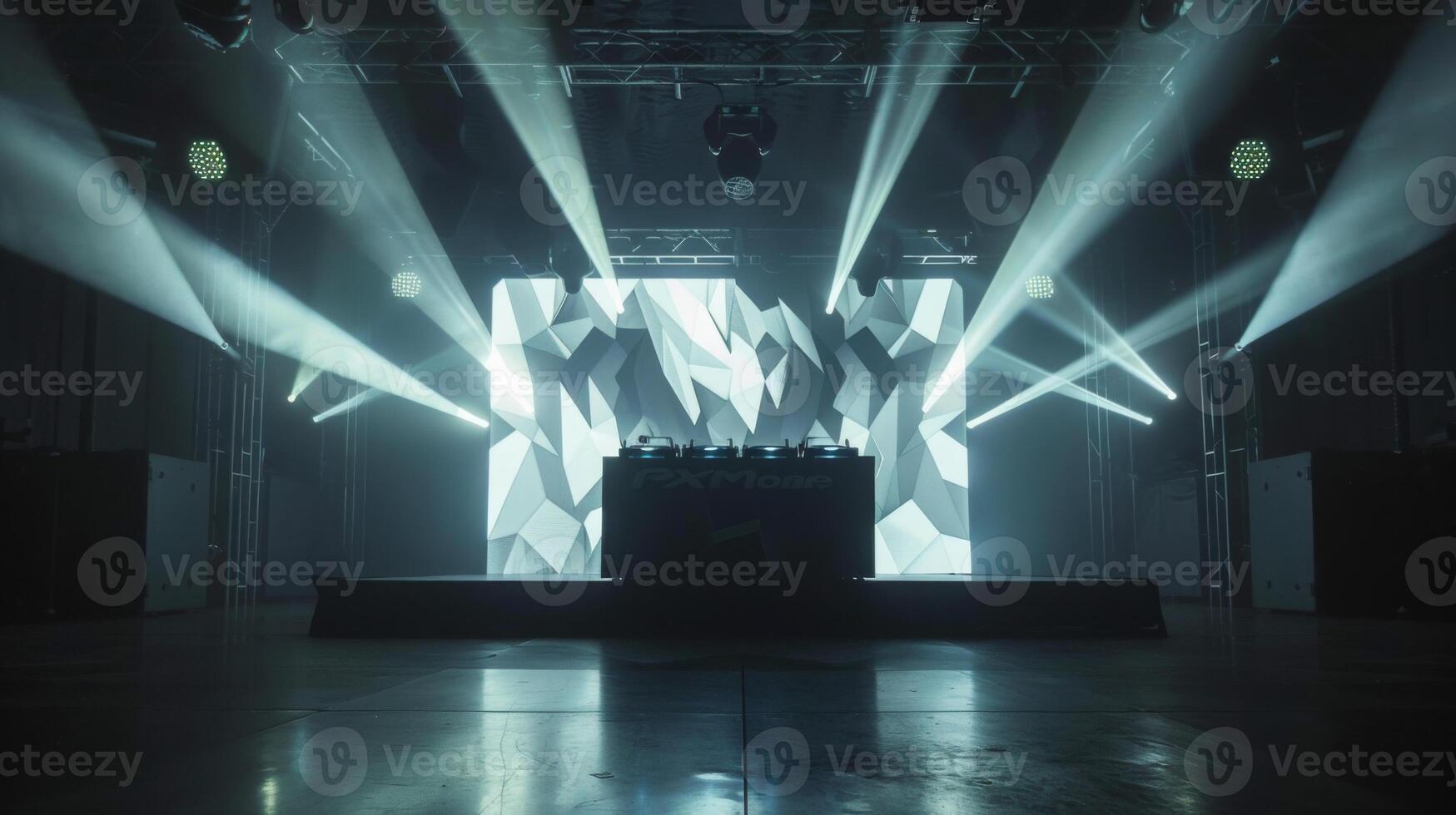 A stage with a DJ setup and a geometric patterned backdrop. The lights are on and the stage is ready for a performance. photo