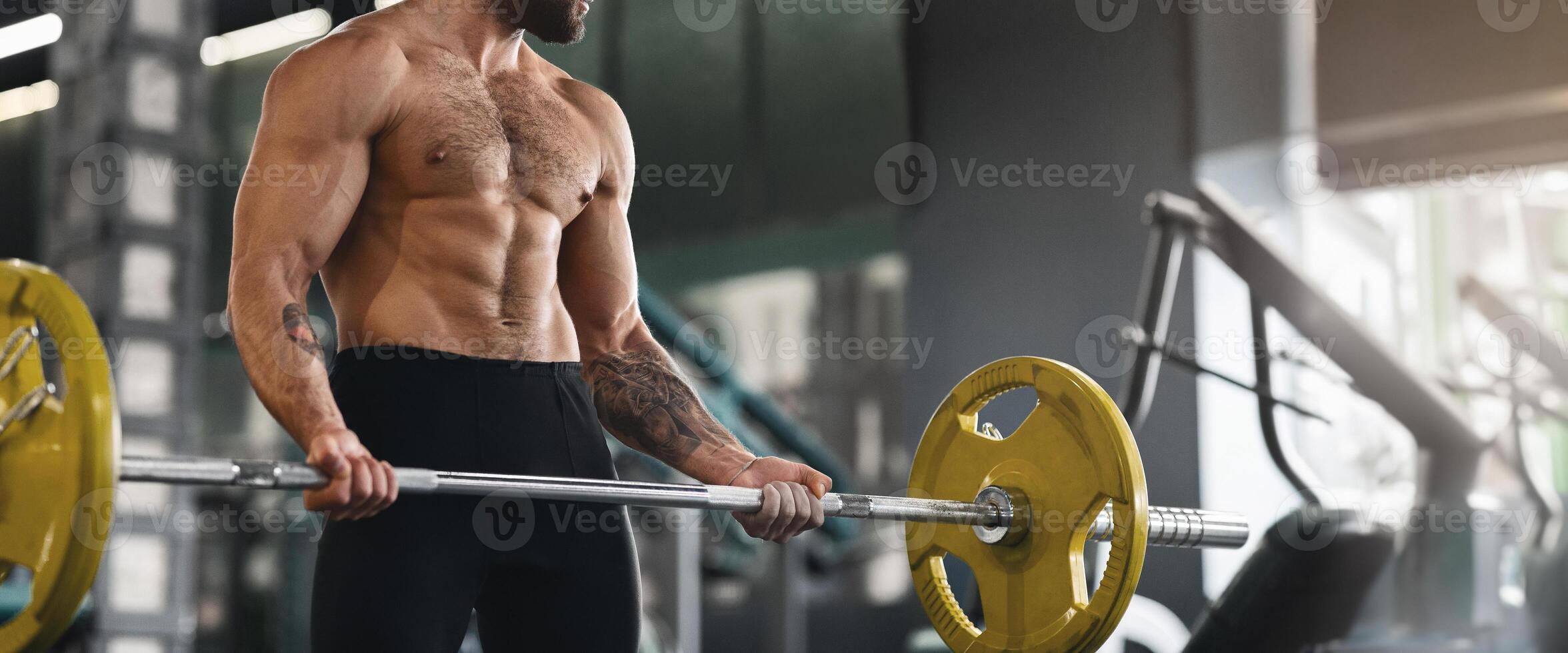 Powerlifting. Muscular guy lifting heavy barbell at gym, panorama with copy space photo