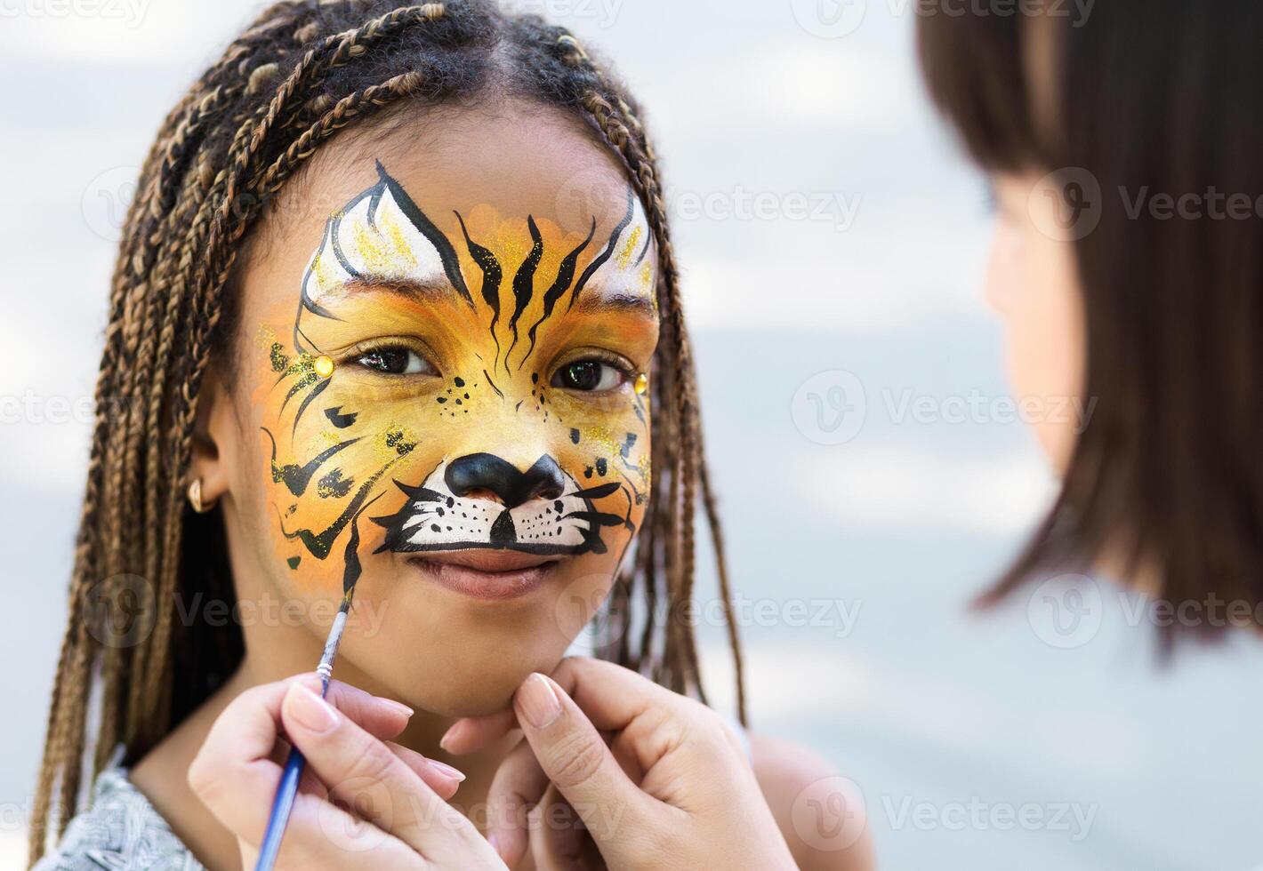 Cute little tiger. African-american girl getting face painting outdoors, having fun, copy space photo