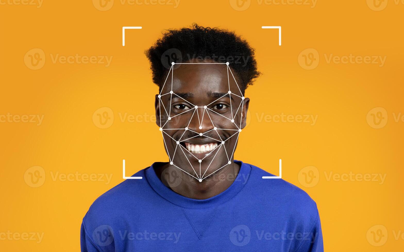 A young black man happily smiles while a facial recognition overlay highlights his features against an orange backdrop. photo