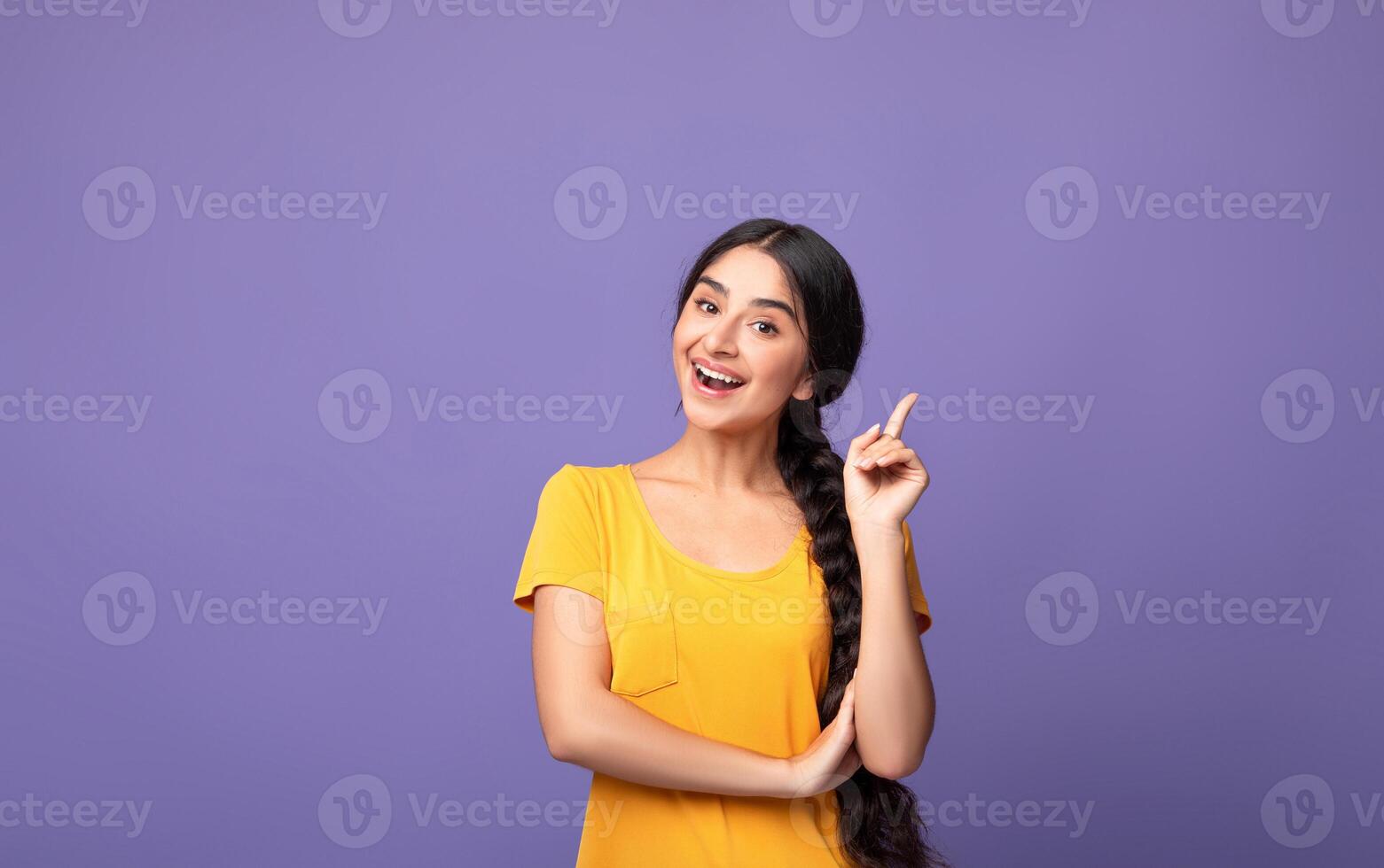 I Have An Idea. Portrait of cheerful young indian woman having great thought, finding inspiration or solution to problem. Positive lady pointing finger up isolated over purple studio wall, copy space photo