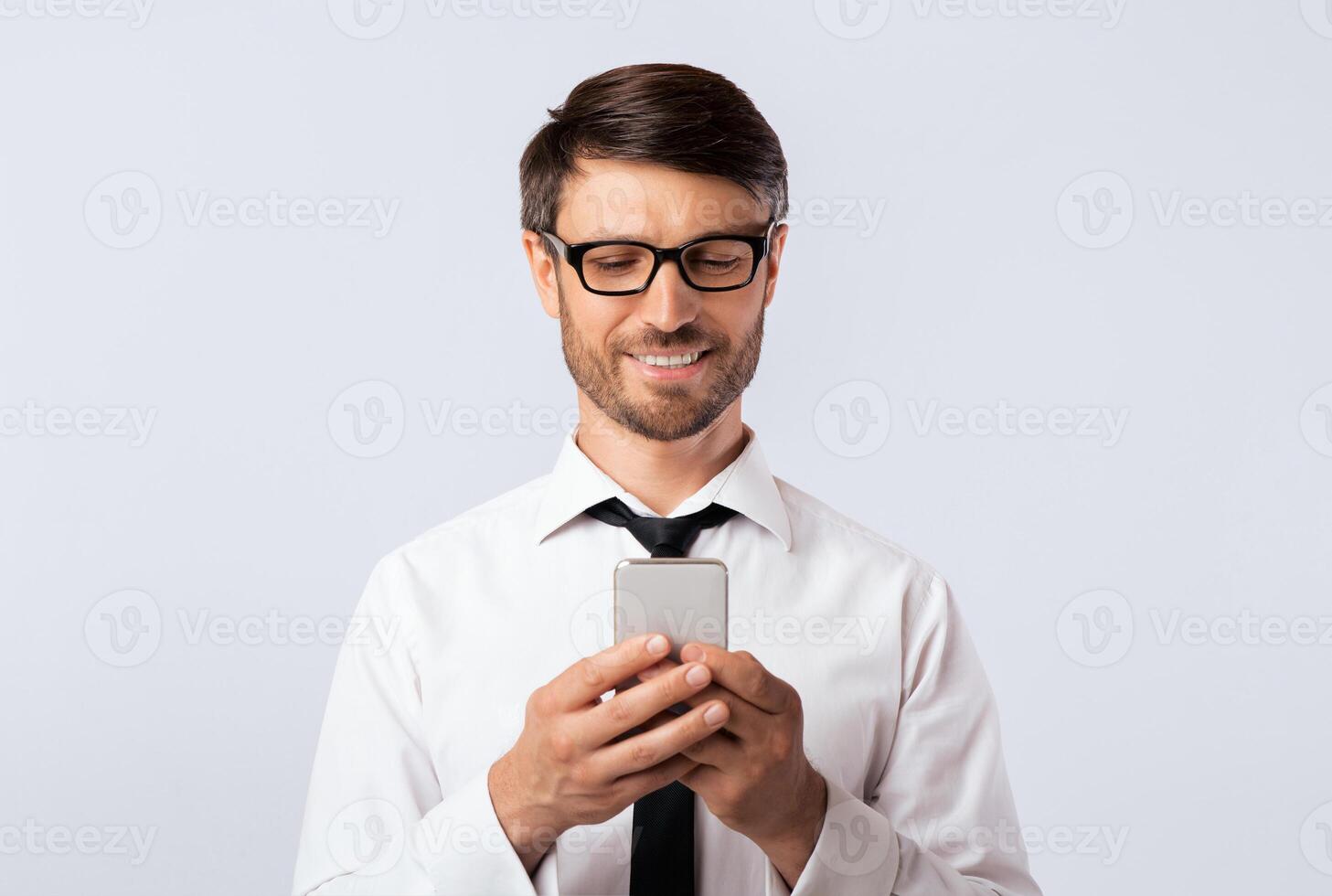 Business Chat. Smiling Man Texting On Cellphone Over White Studio Background. Empty Space photo