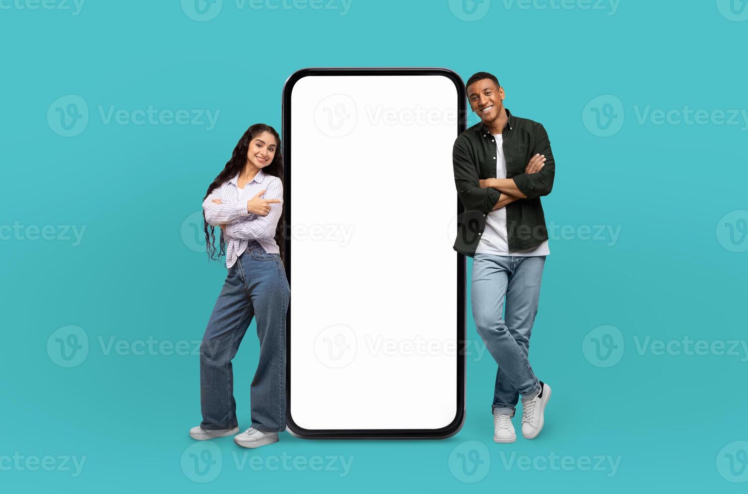 Positioned on a striking blue backdrop, the young multiracial man and woman, both beaming, flank a giant smartphone awaiting your personalized content on its screen. photo