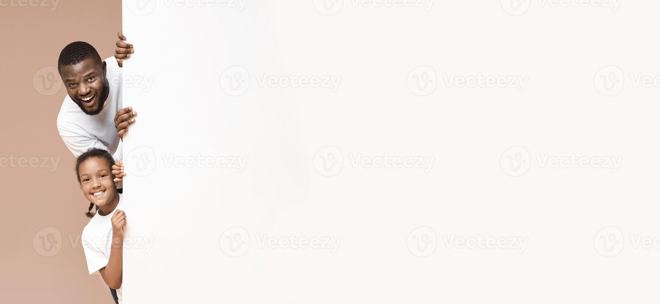 Place For Your Ad. Cheerful African American Father And Daughter Peeking Out Of Blank White Board Over Yellow Background, Panorama photo