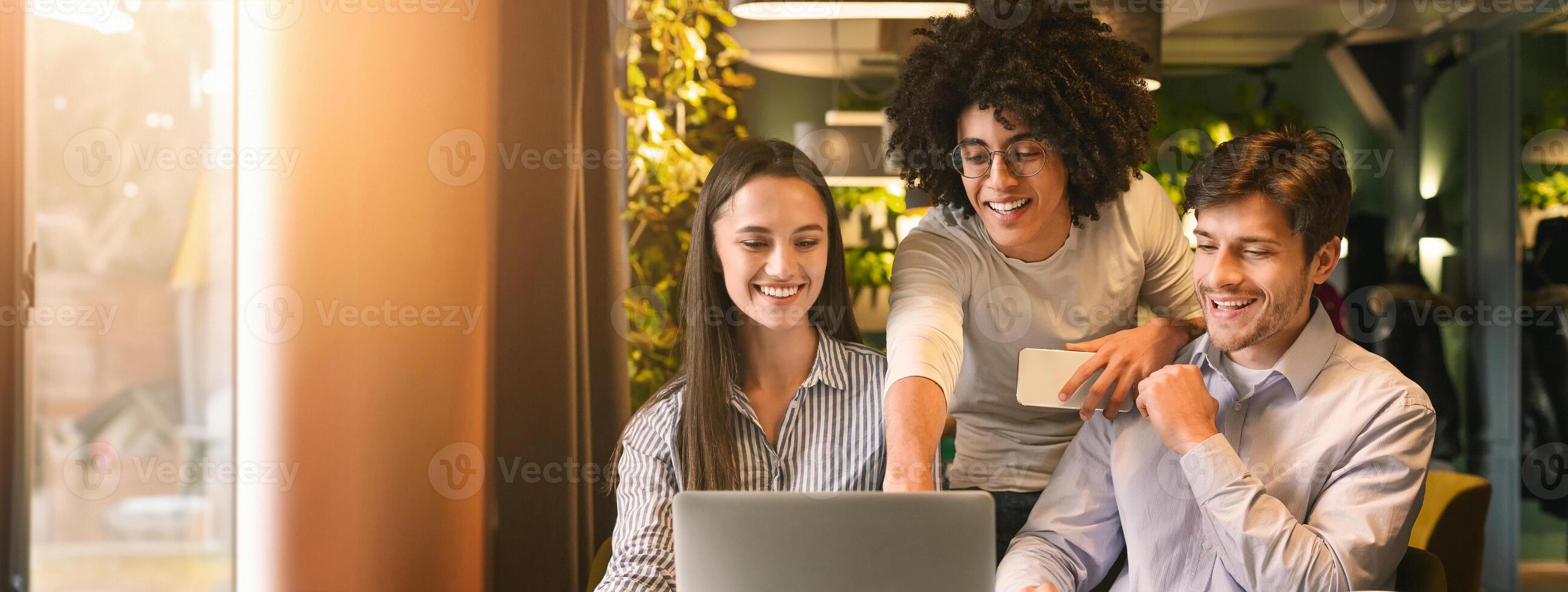 Three young multiethnic professionals engage in a collaborative work session at a cozy cafe, sharing ideas and insights on a laptop, copy space photo