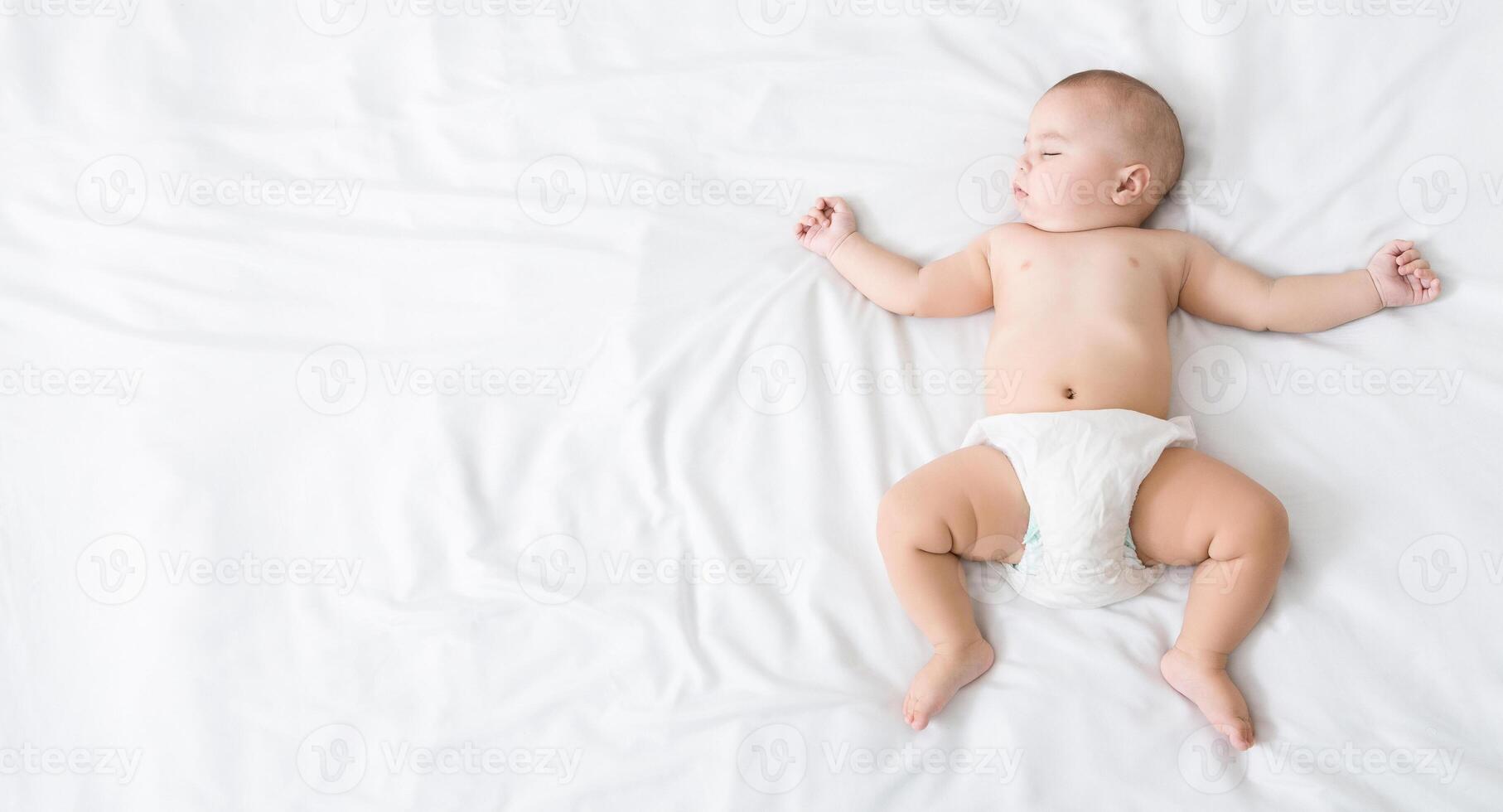 Cute newborn baby in diaper napping on white blanket with his arms up, top view, copy space photo