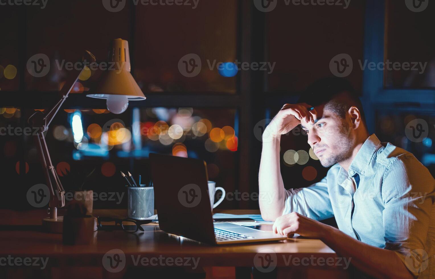 Hardworking Businessman At Laptop Working Overnight On Business Project Sitting In Modern Office Late At Night. Empty Space photo