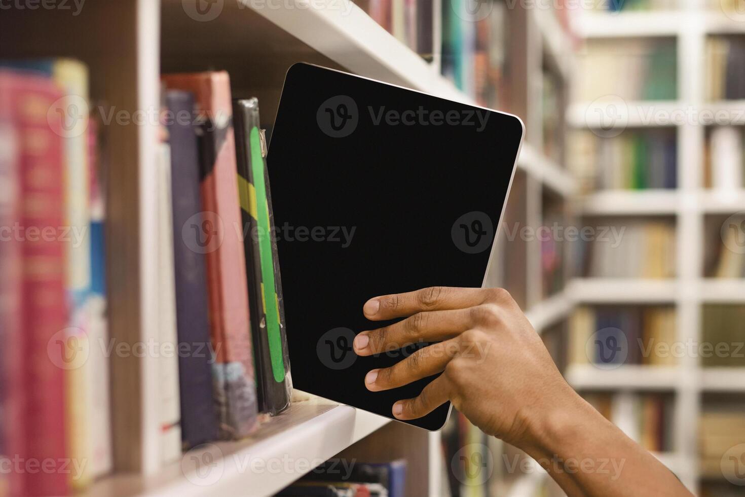Modern technologies and information. Student putting digital tablet with blank screen in shelf in library, free space photo