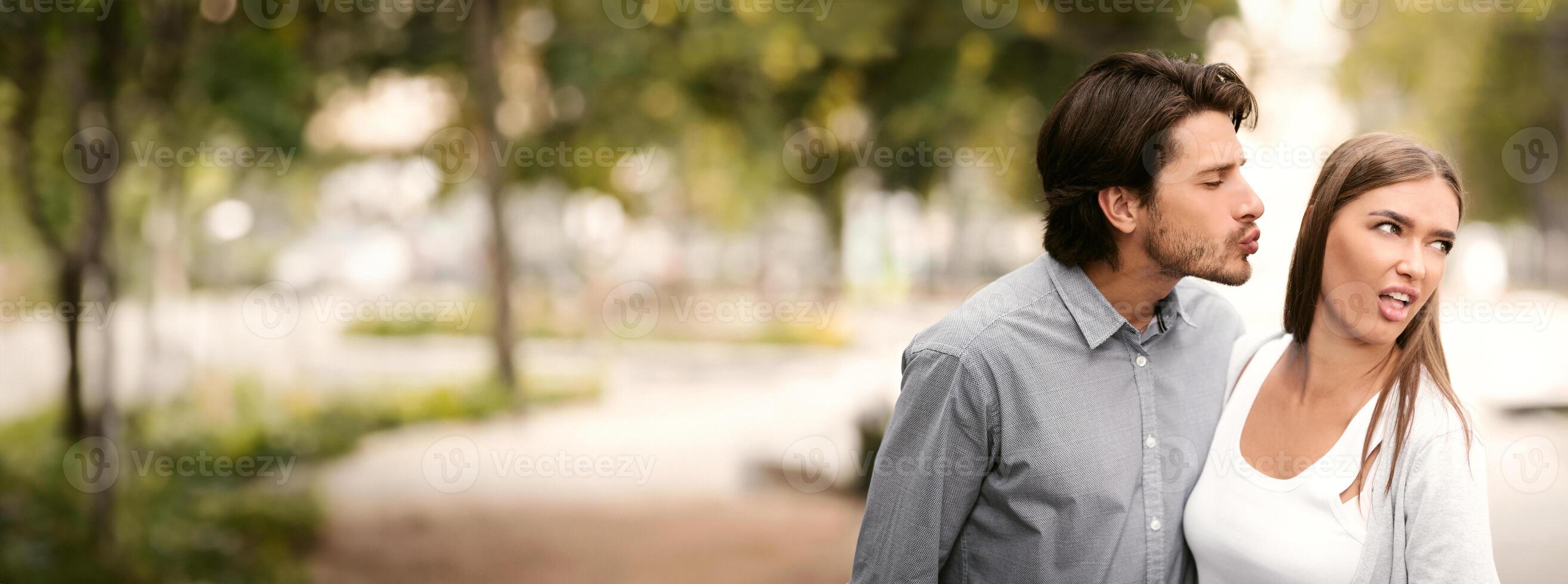 Disgusted Woman Rejecting To Kiss Man Having Bad Date Walking Outdoors In Park. Unanswered One-Sided Love Concept photo