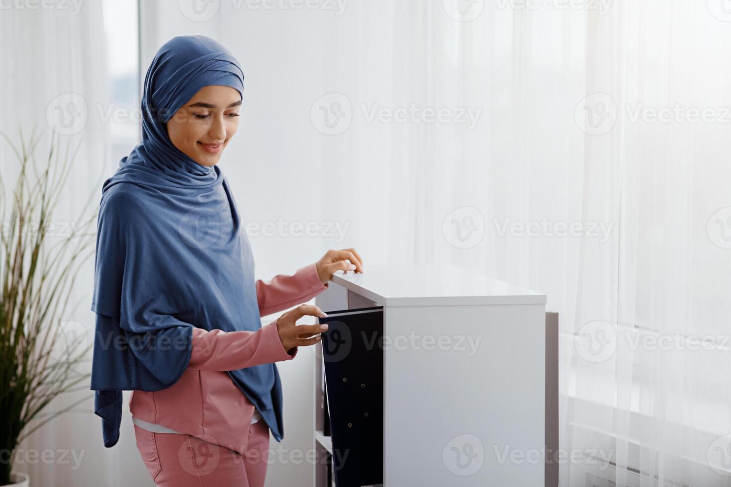 Workspace Management. Young arabic secretary taking folder with documents from archive in modern office, free space photo