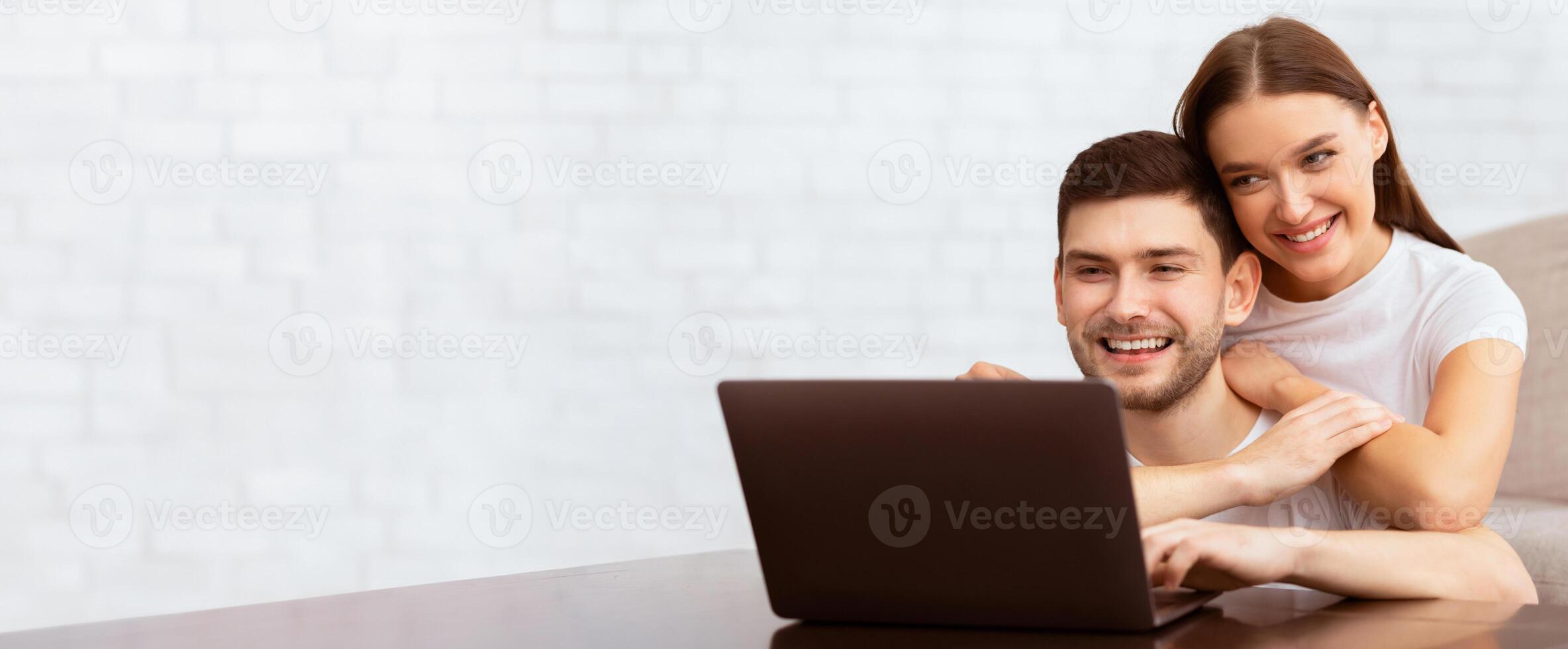 Freelance Lifestyle. Happy Guy Working On Laptop Sitting With Girlfriend On Couch At Home. Selective Focus photo