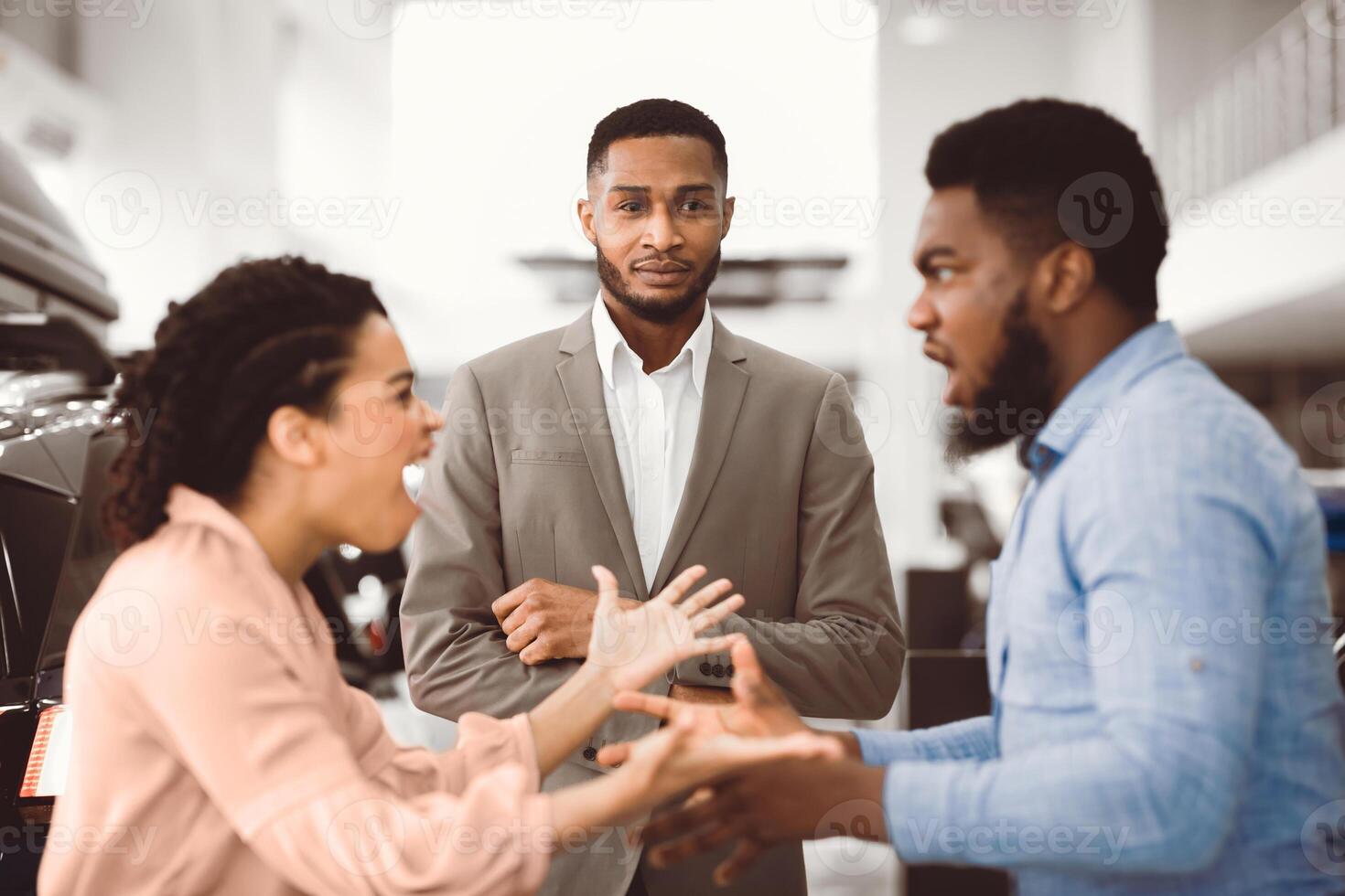 Too Expensive Car. Dealer Looking At African Spouses Having Quarrel About Buying Vehicle Standing In Dealership Store. Selective Focus photo