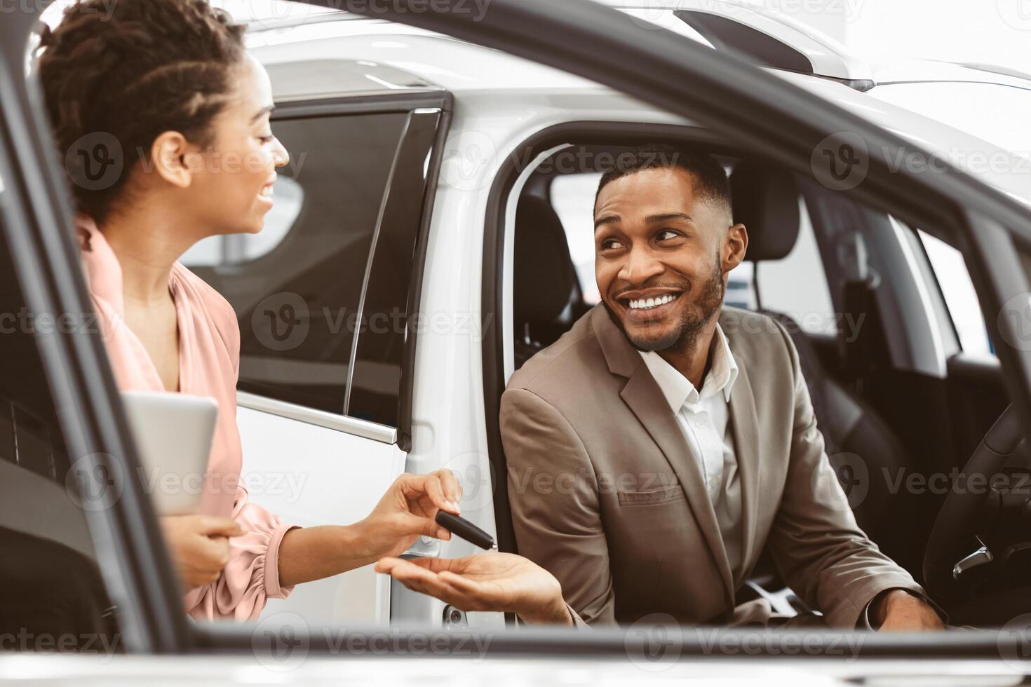 Car Buyer. Black Businessman Choosing Auto Taking Key From Dealer Lady For Test Drive In Dealership Store. Selective Focus photo