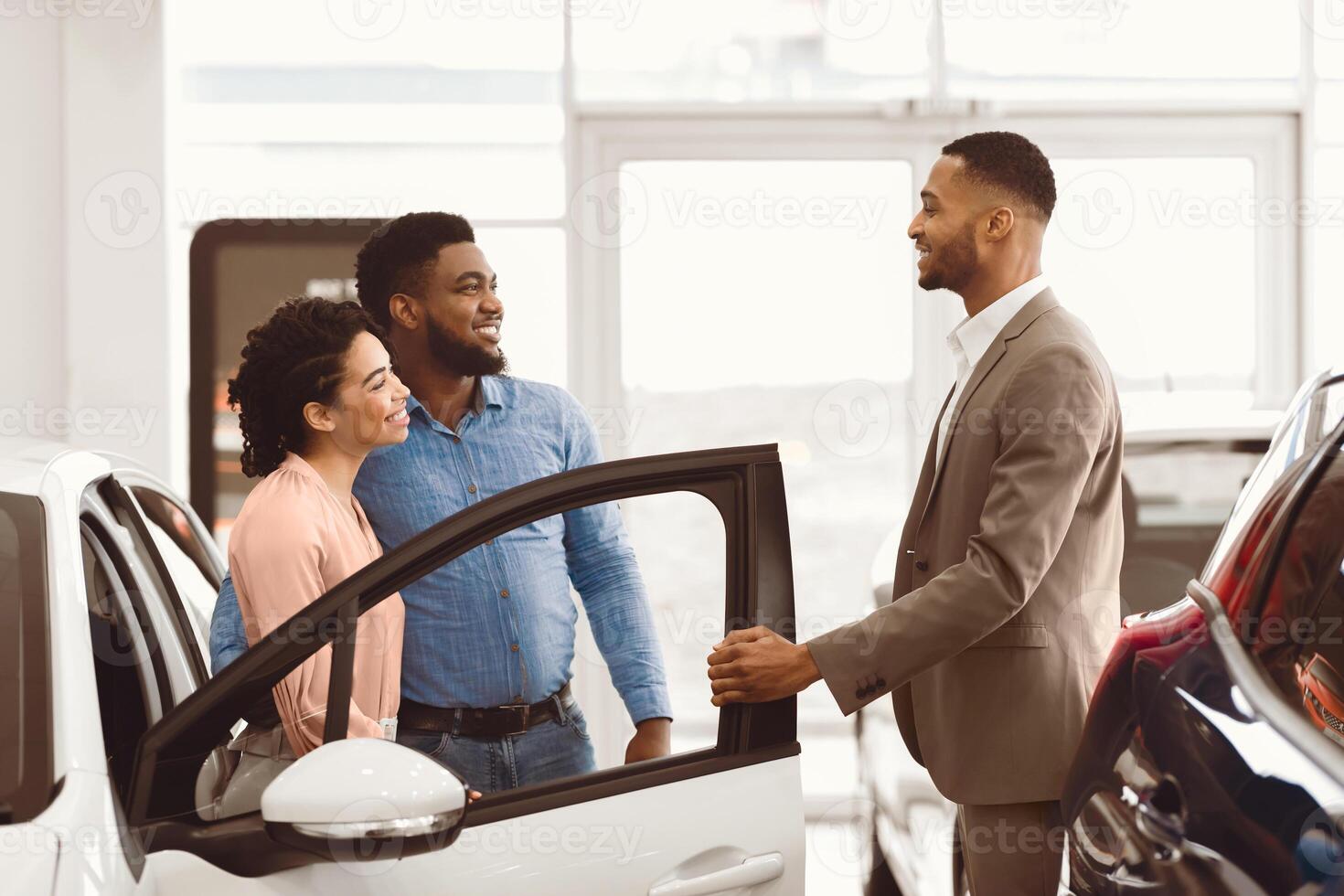 Car Seller Man Consulting Buyers Showing Luxury Auto In Dealership Shop. Car Sales Concept photo